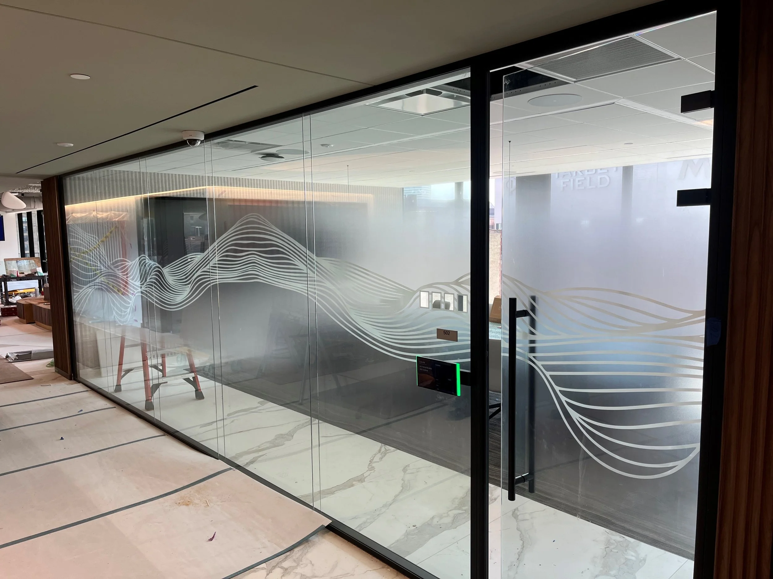 Installed frosted decorative window film with custom wave pattern on glass conference room walls at KPMG office in Minneapolis, Minnesota.