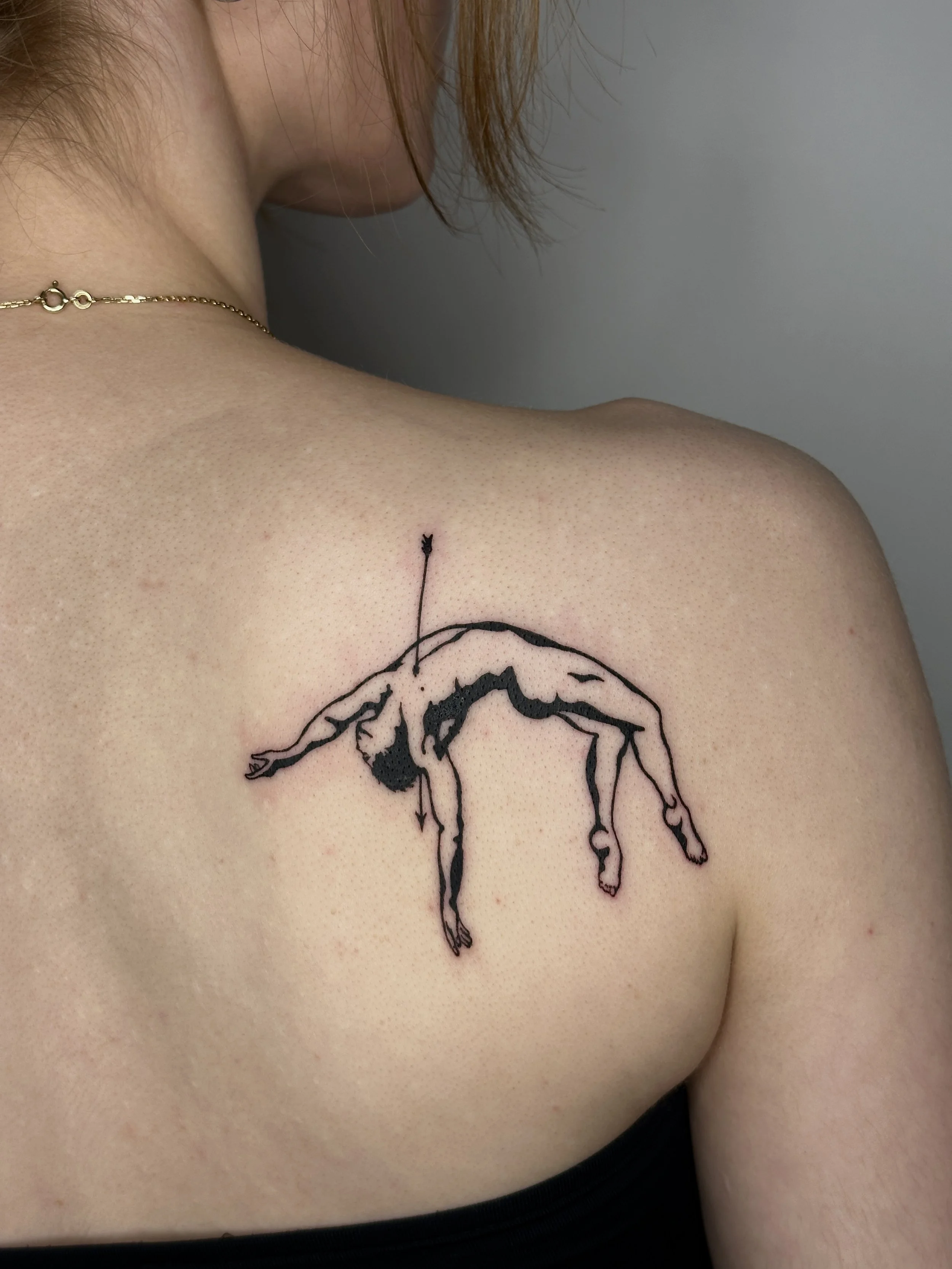 Tattoo eines toten Körpers, der mit Pfeil im Oberkörper auf der Schulter einer Person tätowiert ist.