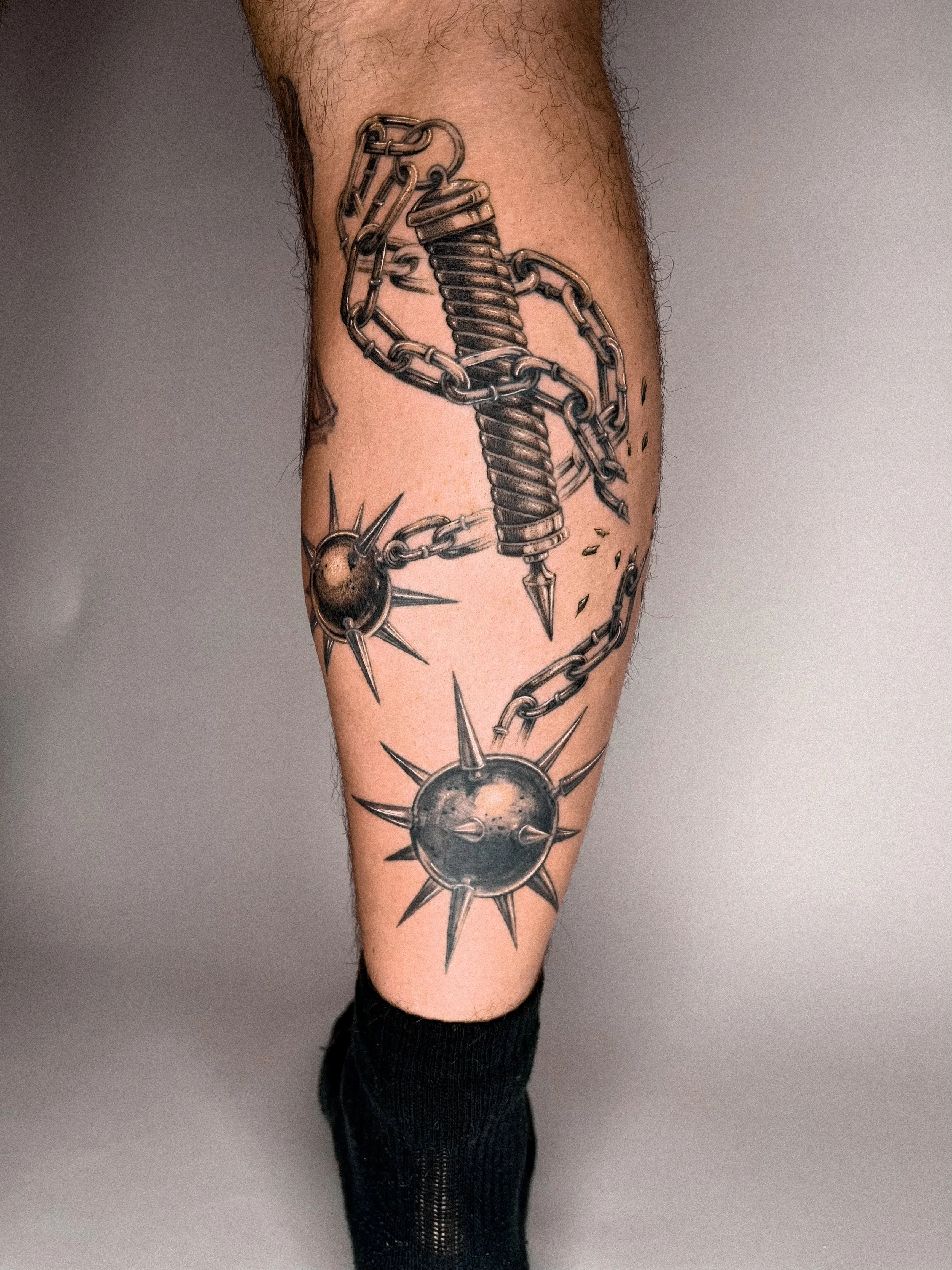 Tattoo eines Hammers mit Ketten und kinetischen Kugeln am Unterschenkel