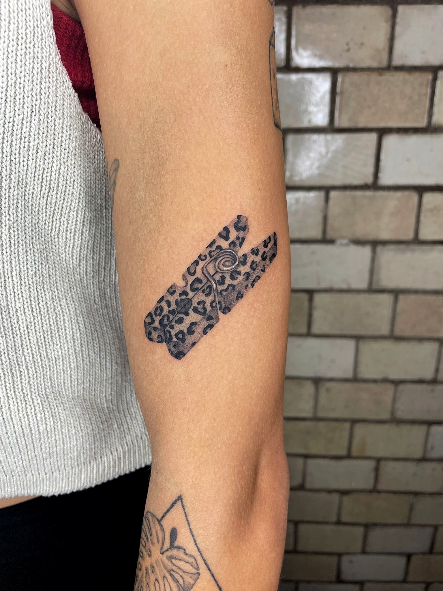 Tattoo eines Leiters mit Leopardenmuster auf dem Oberarm.