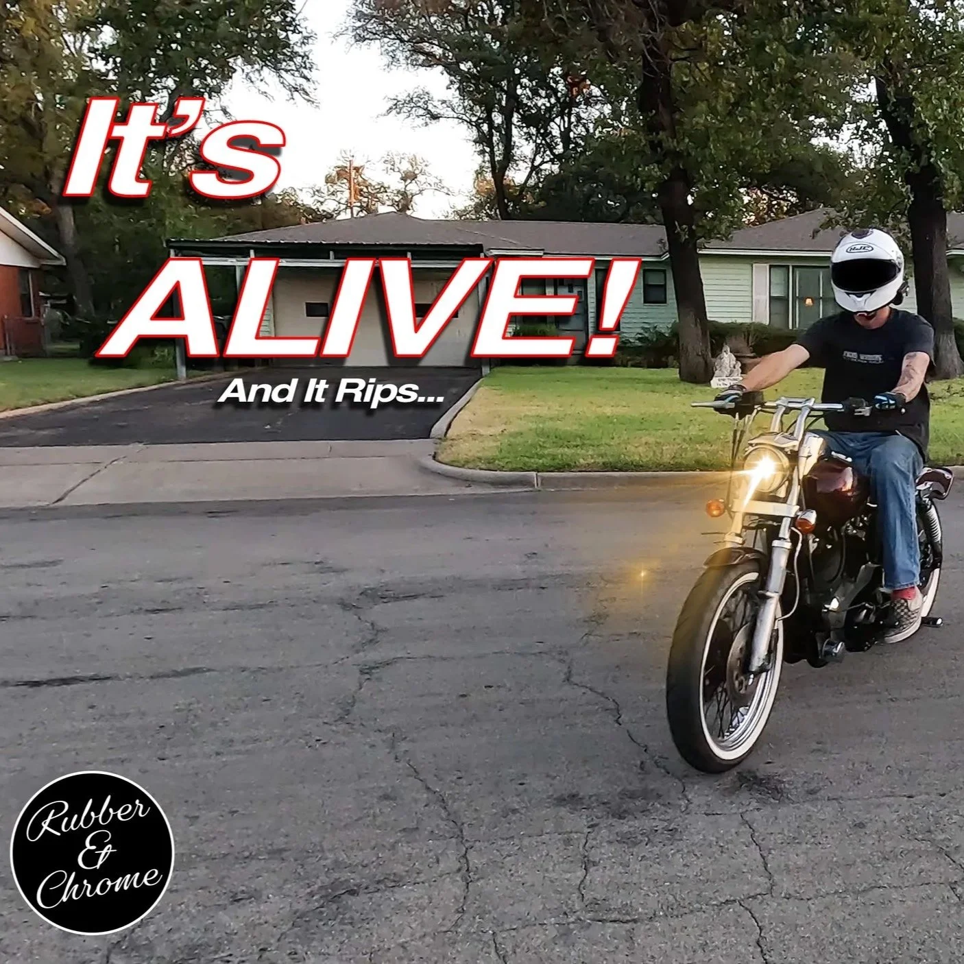 A person riding a motorcycle on a residential street with a house and trees in the background. Text overlay says 'It's ALIVE! And It Rips...' with a logo that says 'Rubber & Chrome'.