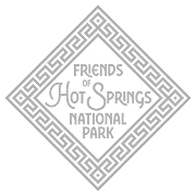 Close-up of a silver or metallic decorative coin or medallion with a textured surface and geometric border, placed on a white background.