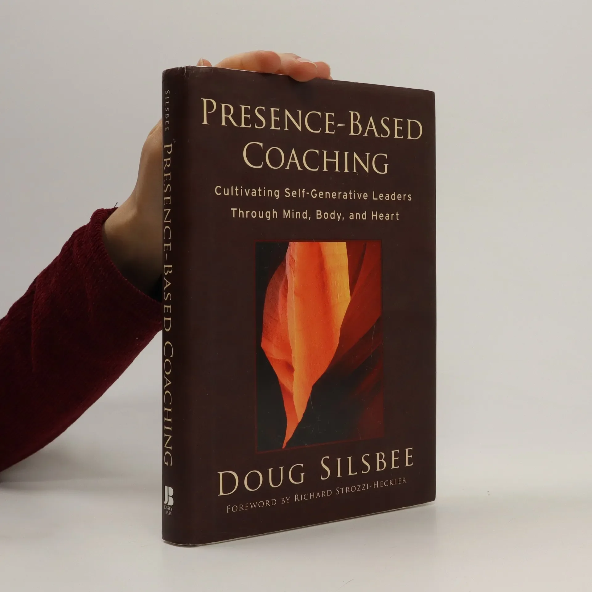 A book titled 'Presence-Based Coaching' by Doug Silsbee, with a subtitle about cultivating self-generative leaders through mind, body, and heart. The cover features an abstract, warm-colored artwork and a foreword by Richard Strozz-Heckler.