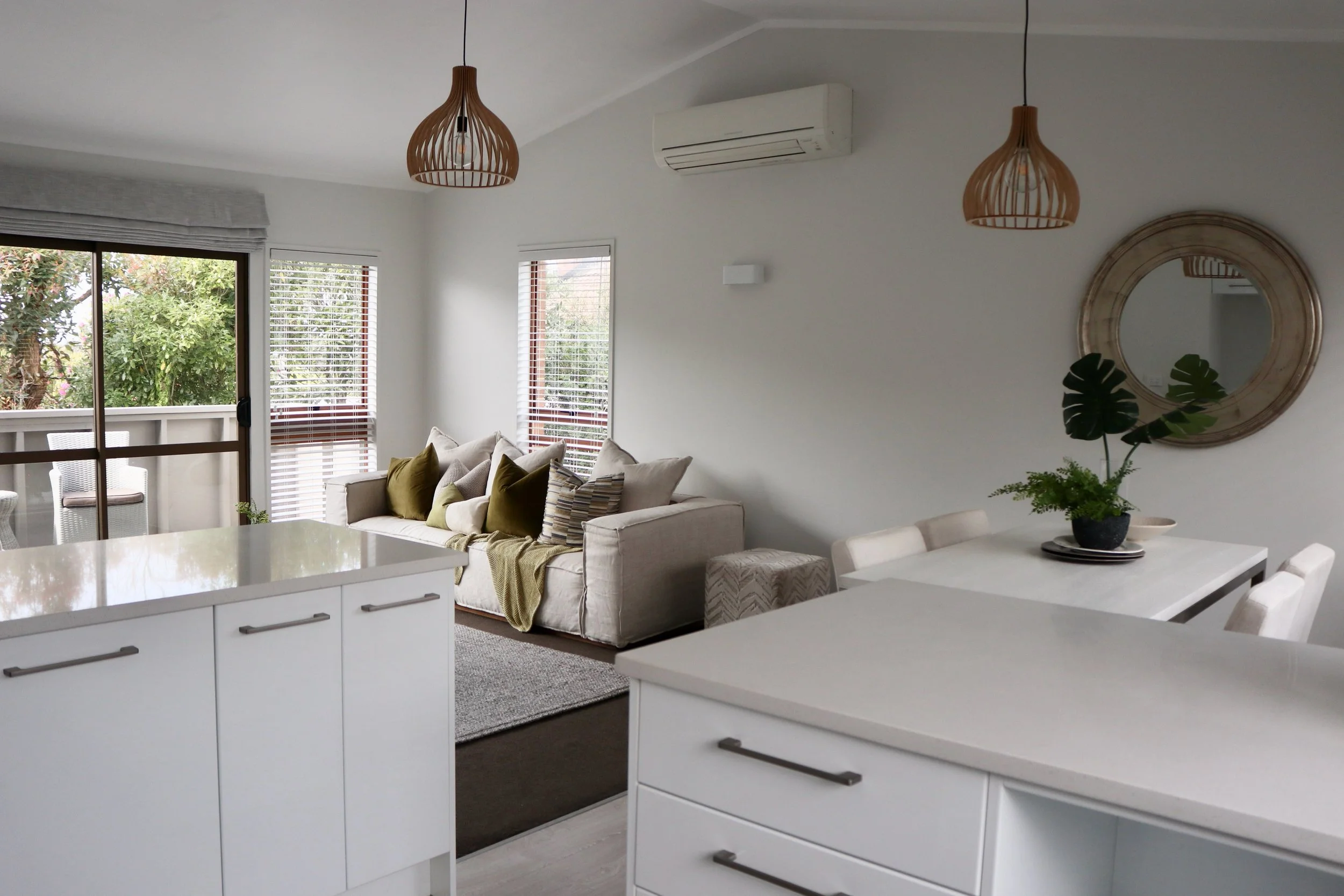 Open-concept living room and dining area with white walls, large windows, and a balcony door.