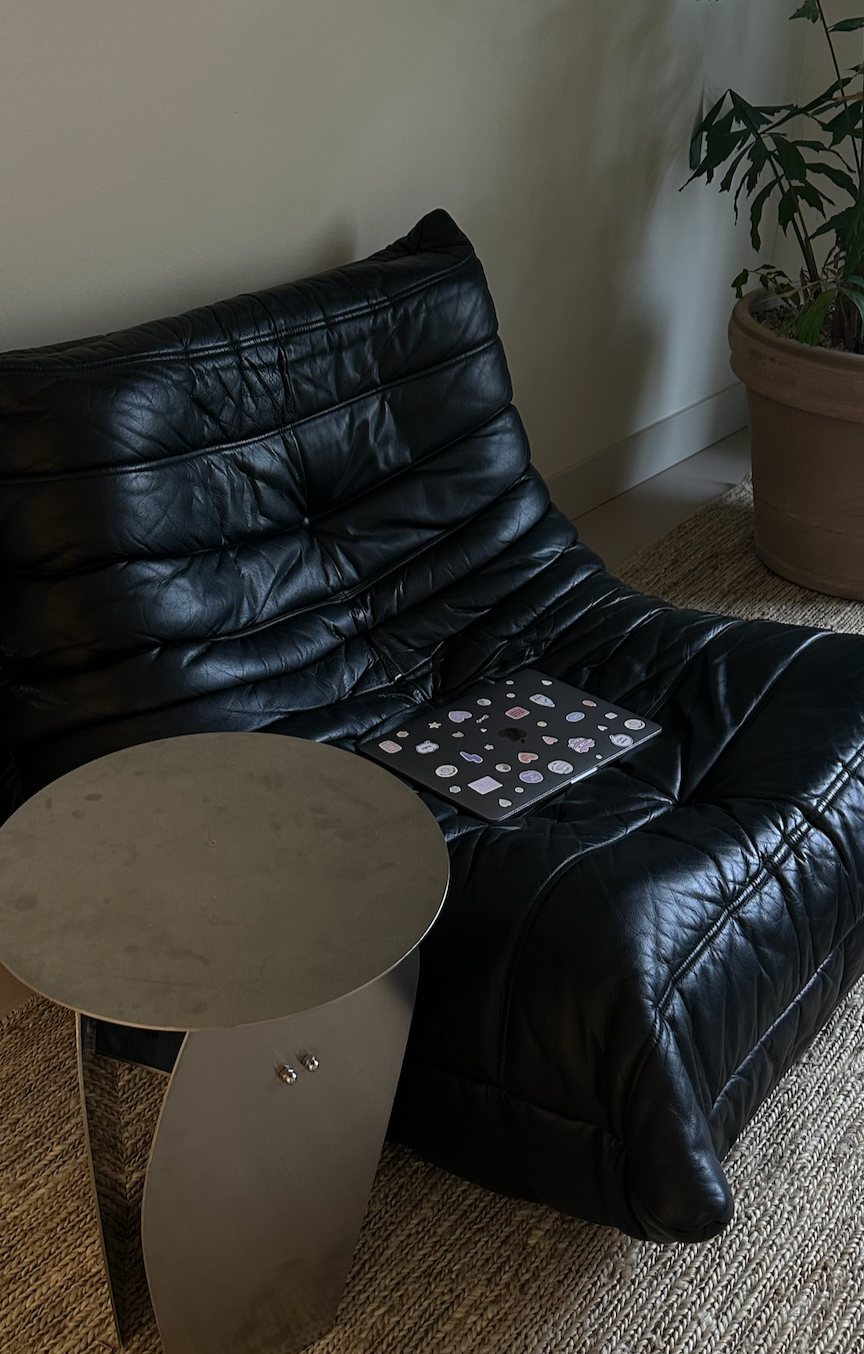 Studio interior with black leather lounge chair with laptop and small round table
