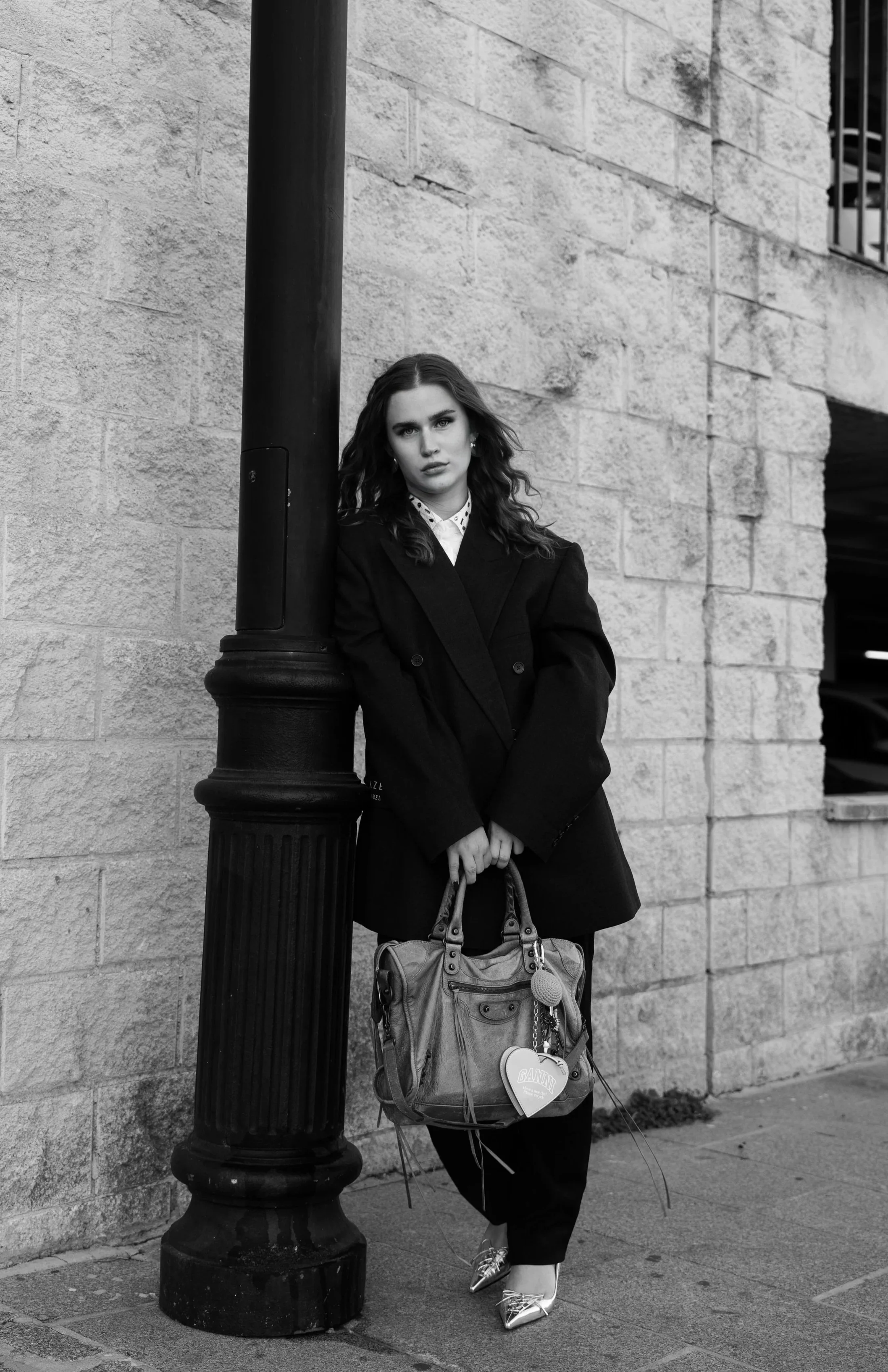 Founder of Studio Charvo standing outdoors holding a bag, black and white portrait