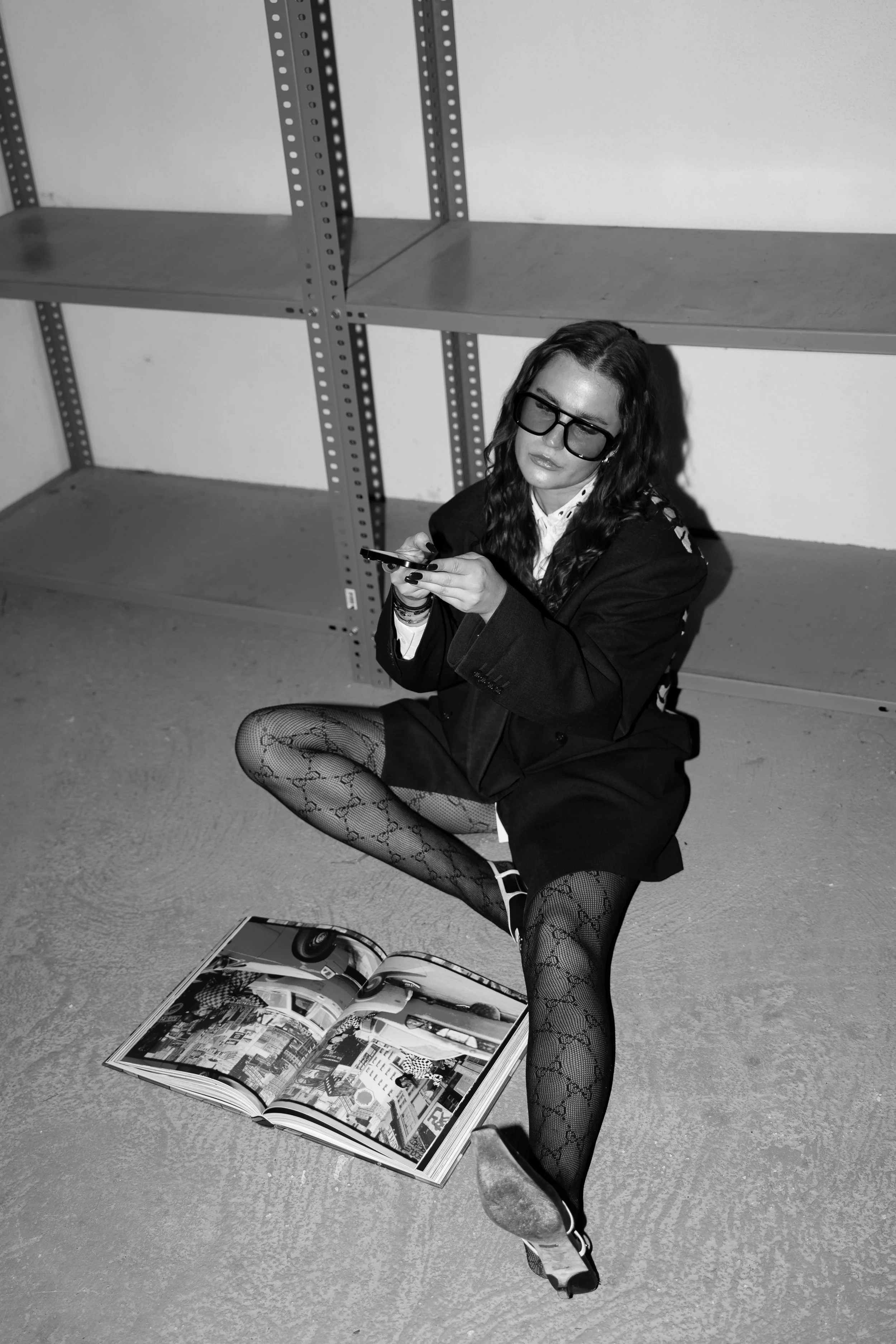 Black and white editorial portrait of the founder sitting with a phone and magazine.