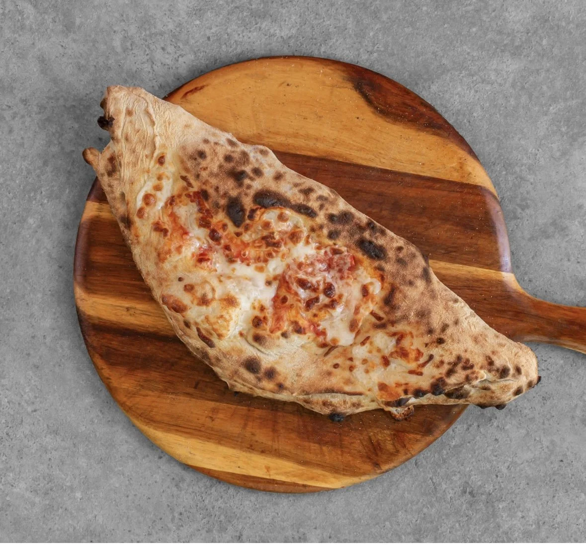 Slice of pepperoni pizza on a wooden pizza peel.