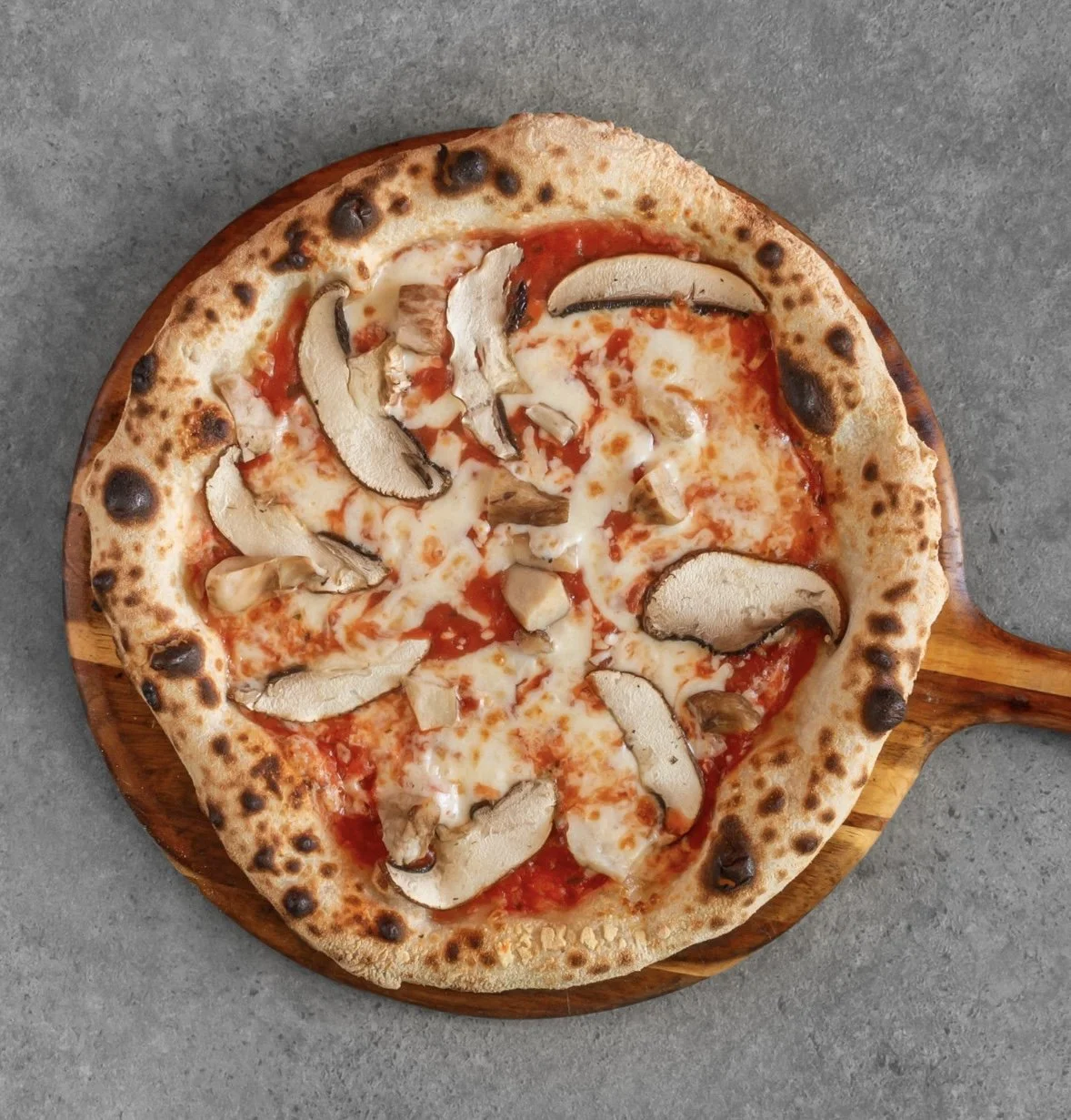 Pizza with mushrooms, cheese, and tomato sauce on a wooden tray