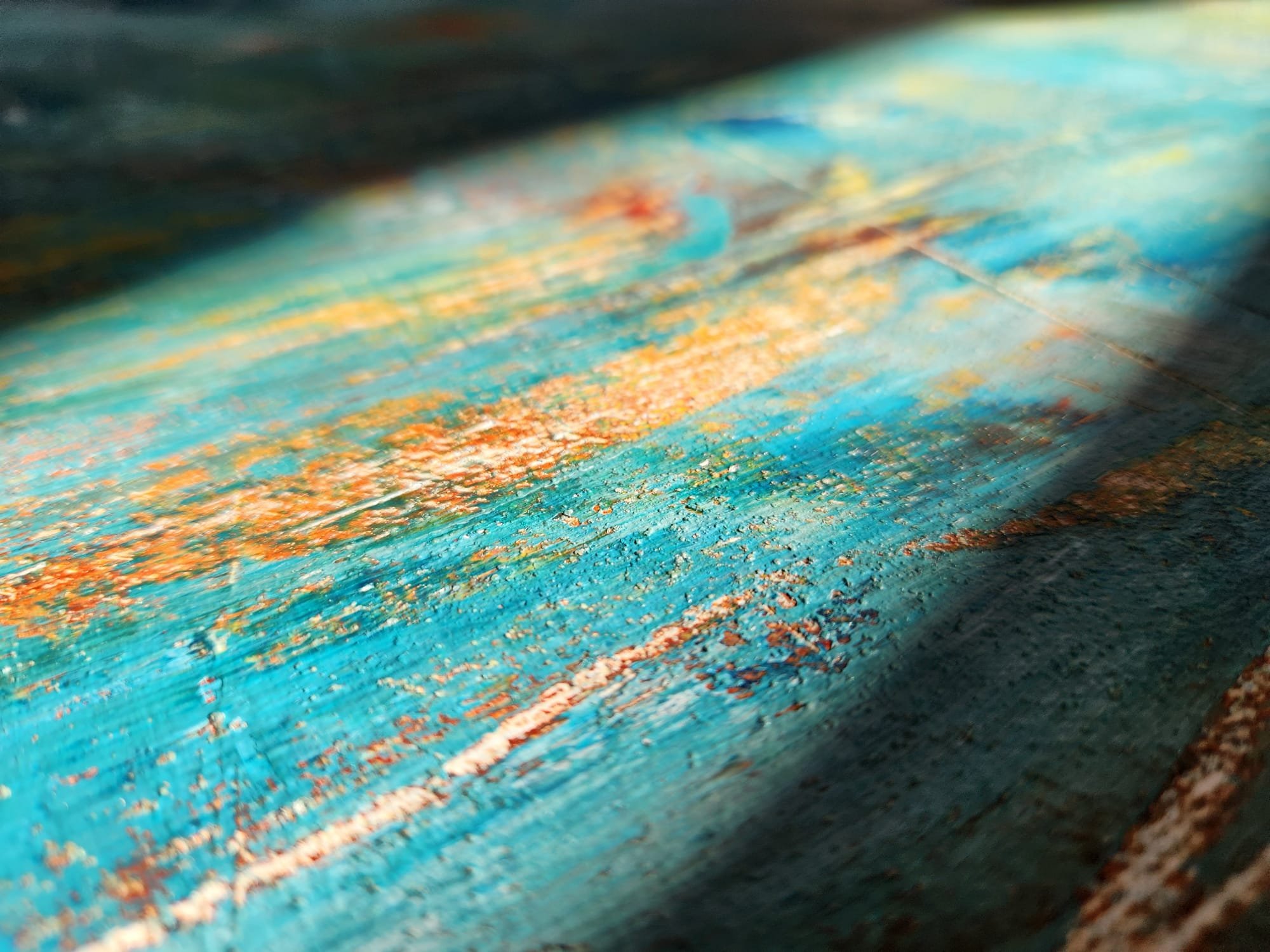Close-up of a colorful, textured abstract painting with shades of blue, green, orange, and white.