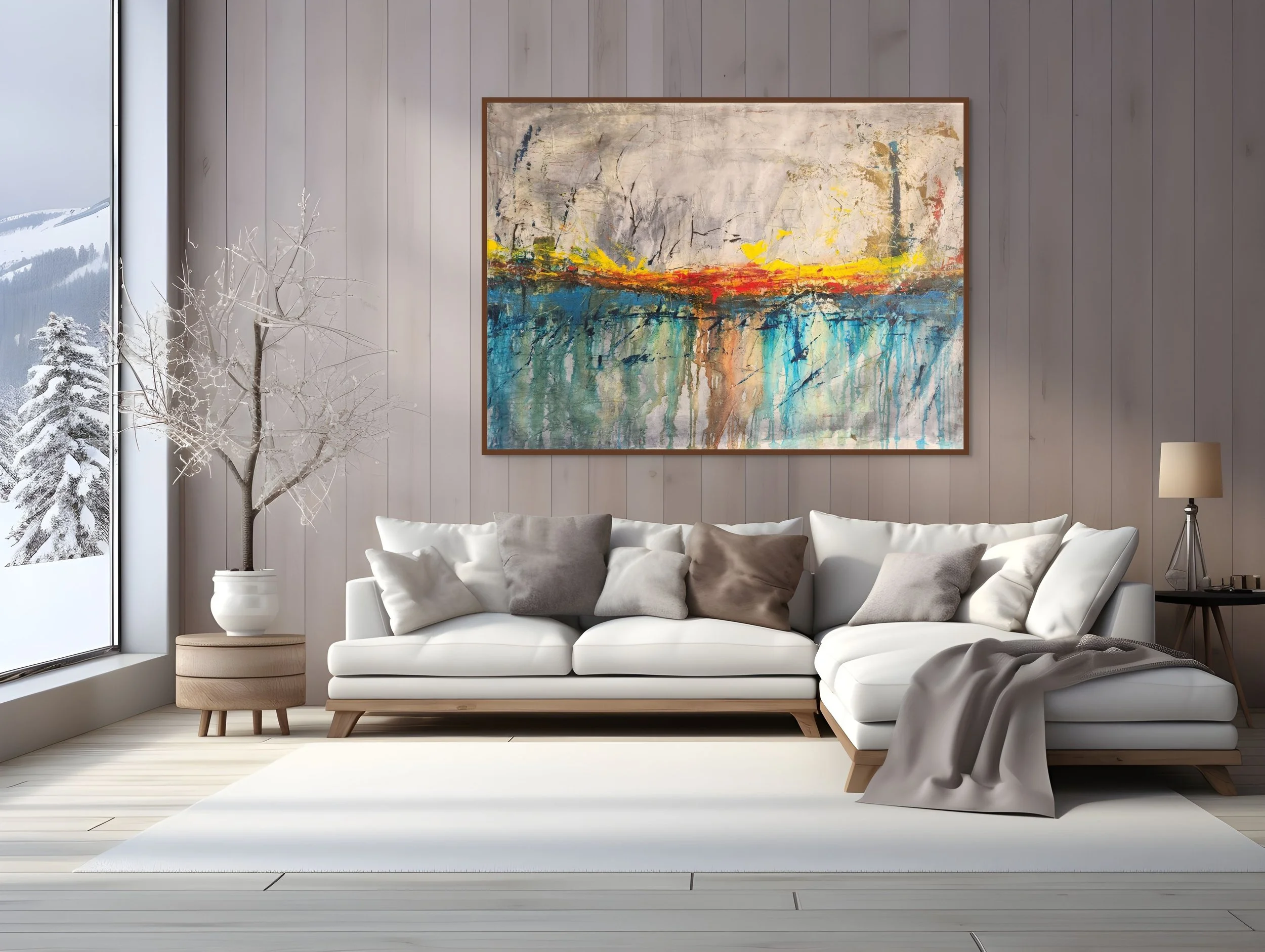 Living room with white sectional sofa, gray and beige pillows, a white rug, a tree in a pot, a large abstract painting, a side table with a lamp, and a floor-to-ceiling window showing snow-covered trees and mountains.
