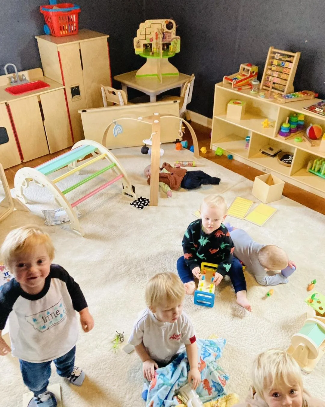 Children playing inside a colorful playroom with toys, books, and furniture.