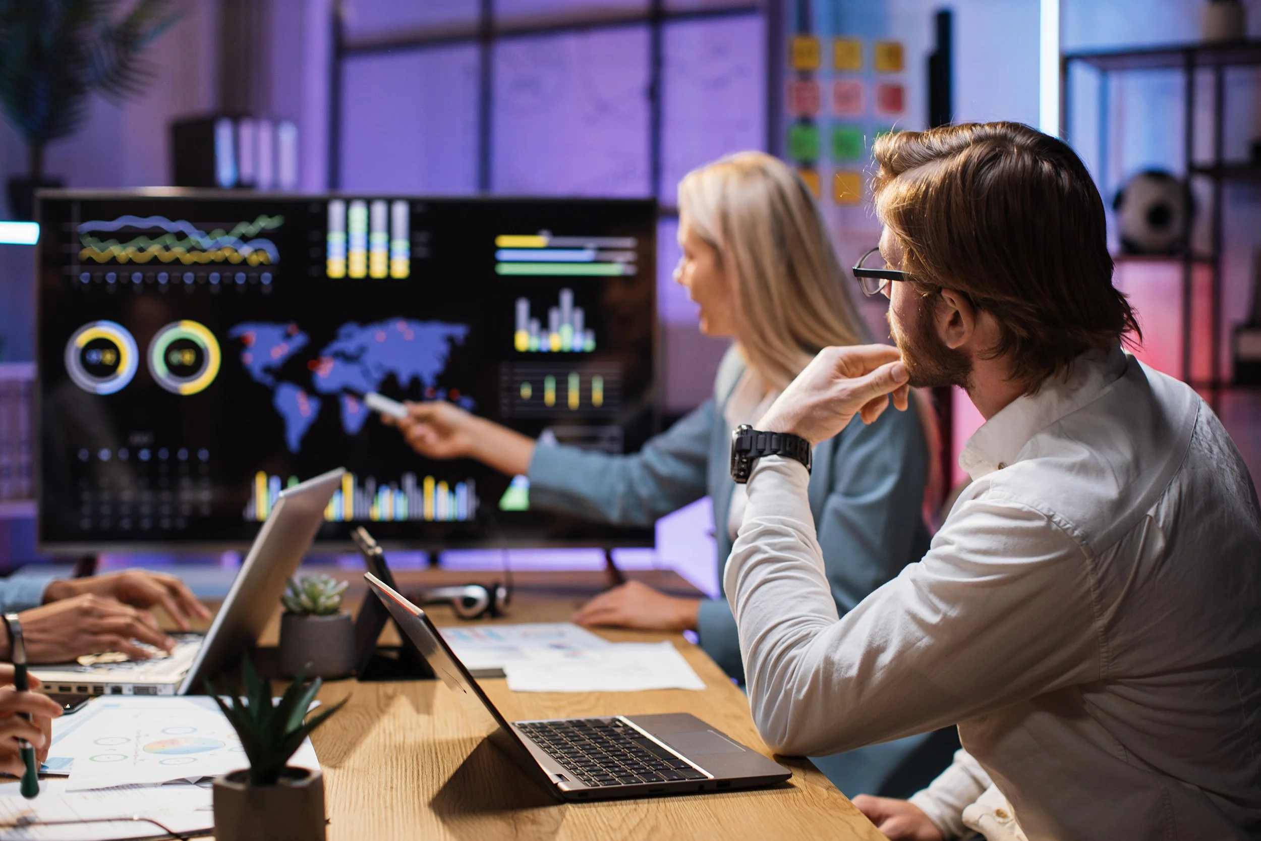 Team in office discussing graphs and charts on monitor.