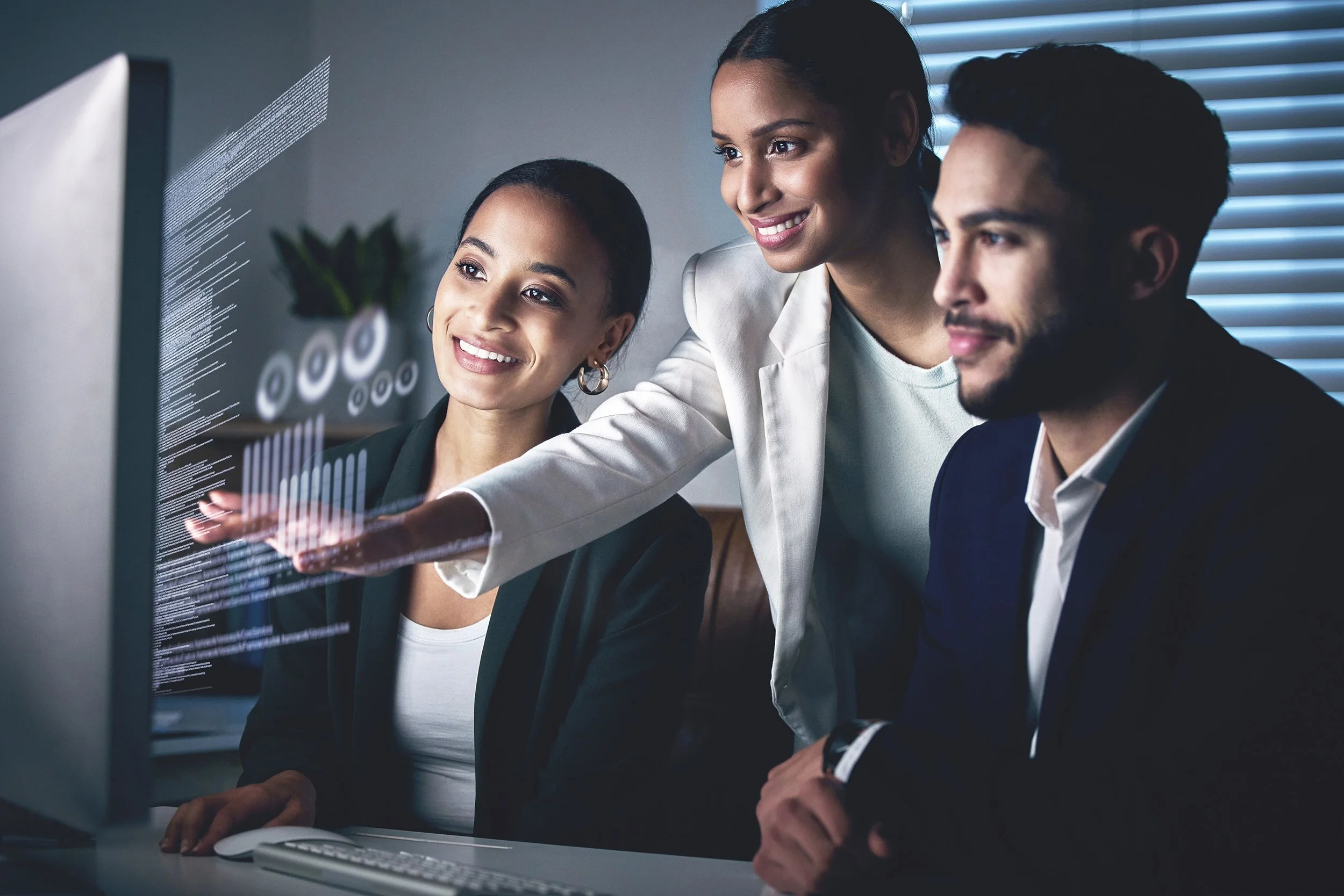 Two woman and one man looking at charts and graphs on a monitor.