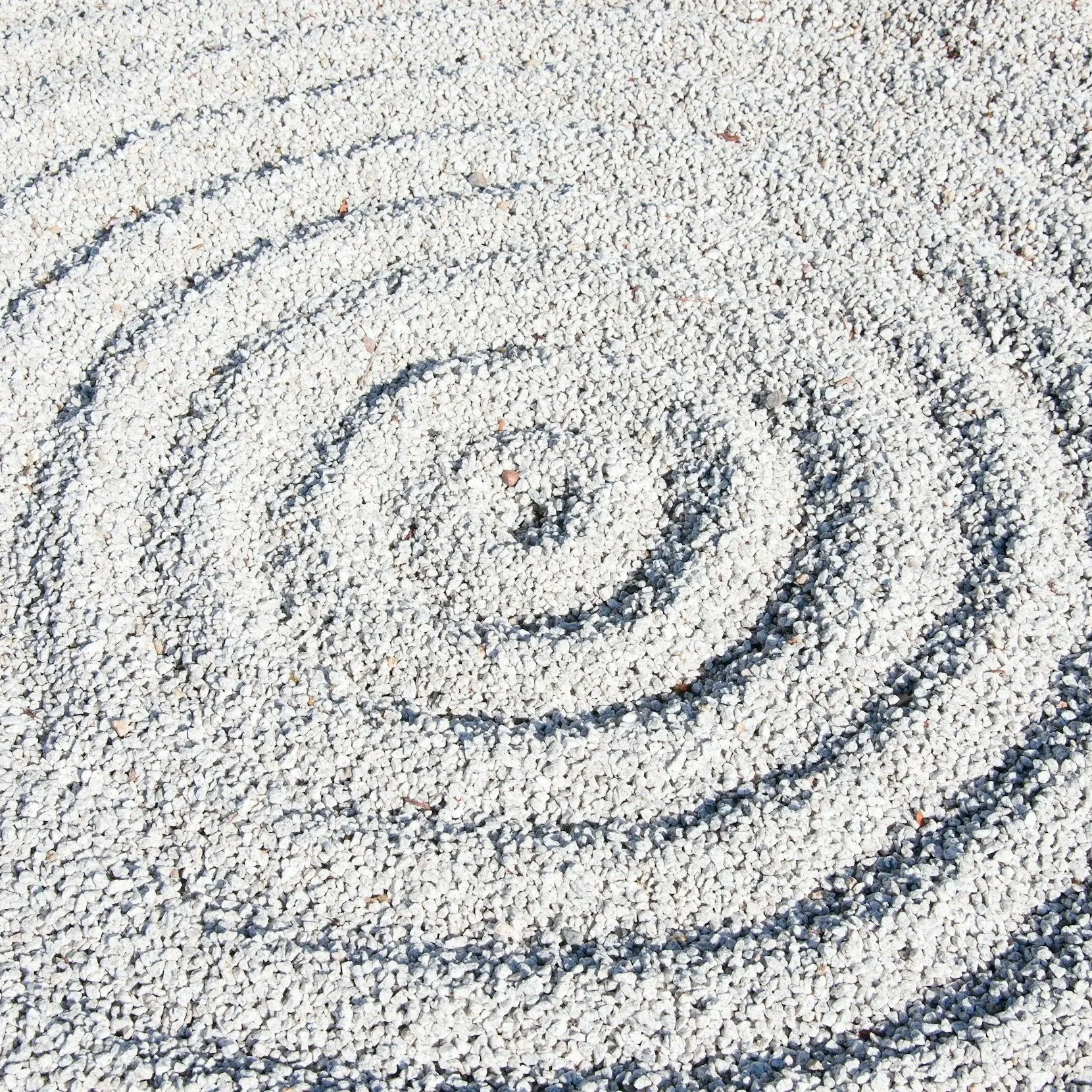Close-up of a spiraling yin-yang symbol drawn in white gravel.