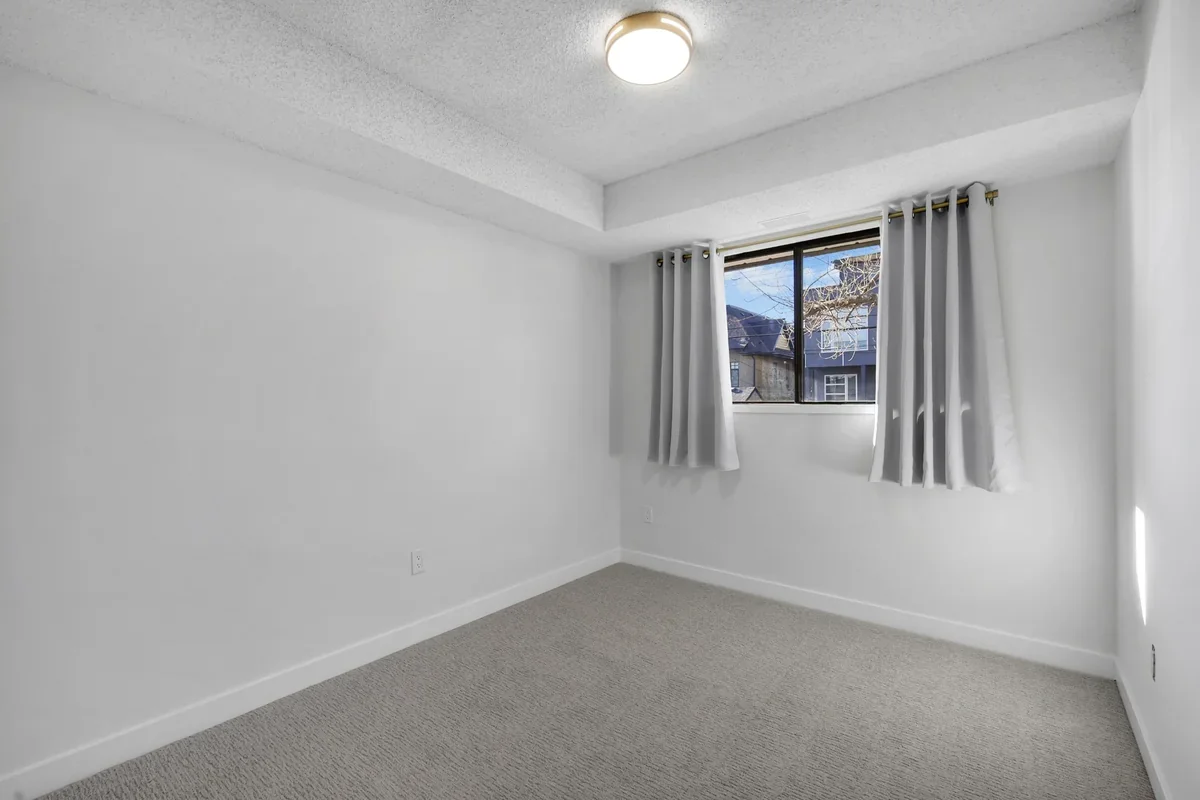 Secondary bedroom renovation in Calgary with fresh paint, new carpet, updated trim, natural light, and clean contemporary finishes completed by Da Vinci Contracting.