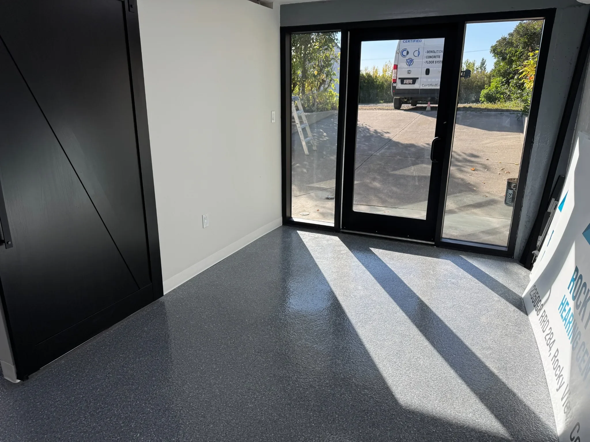 Commercial entryway finished with a smooth grey epoxy floor, providing a clean, durable, and professional look for high-traffic business entrances in Calgary.