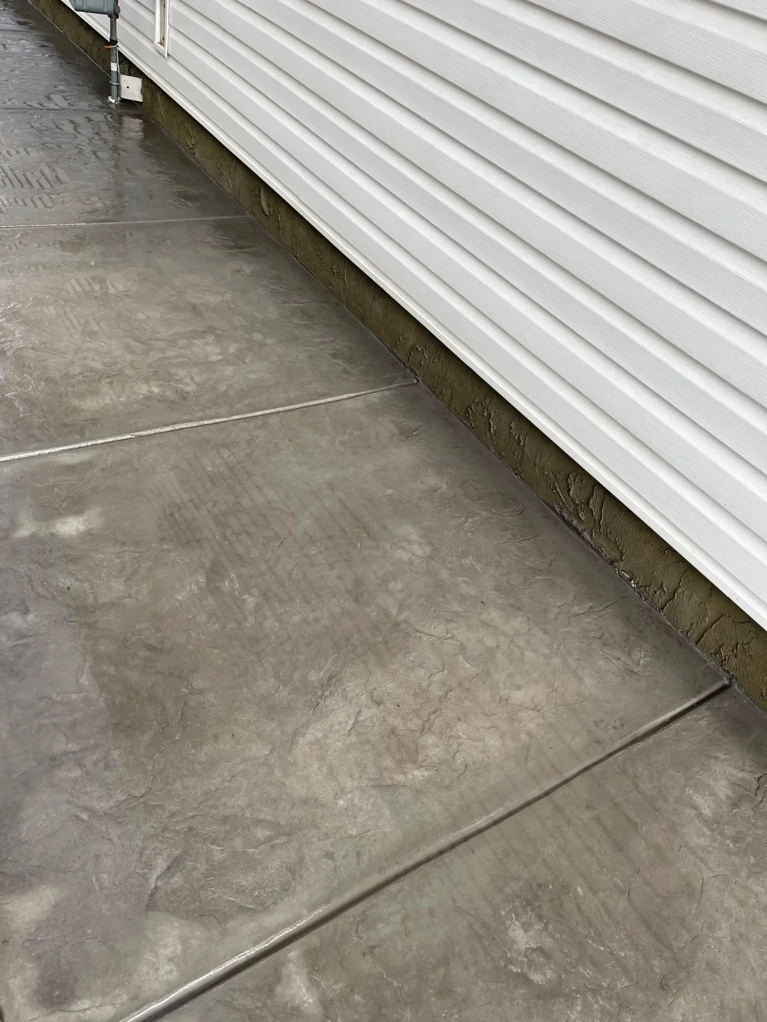 Stamped concrete walkway with a textured stone-style finish, installed along the side of the home for durability and visual appeal. This decorative concrete surface provides a slip-resistant, long-lasting solution suited for Calgary residential walkw