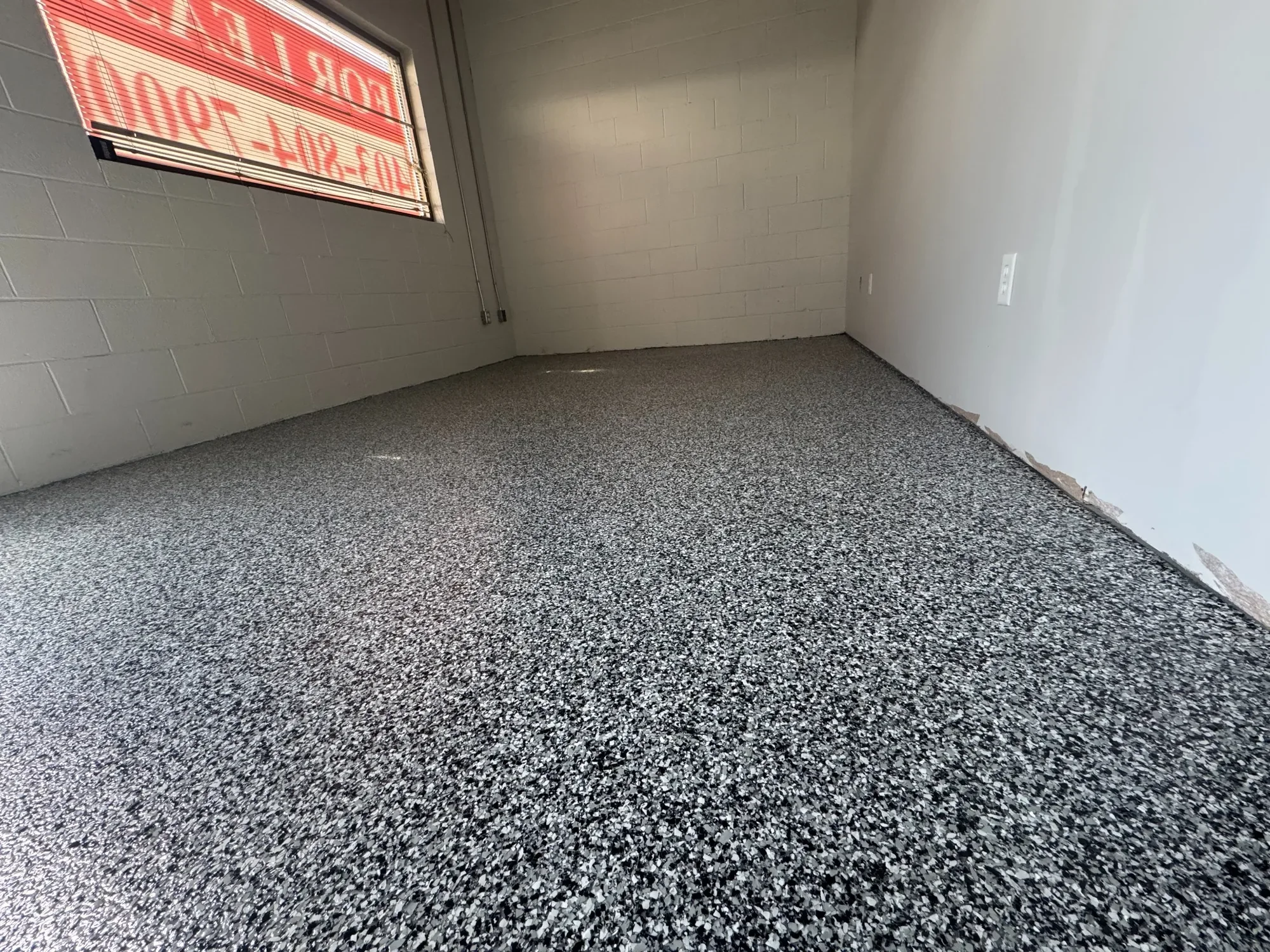 Commercial space upgraded with a durable grey flake epoxy floor, ideal for high-traffic and professional environments.