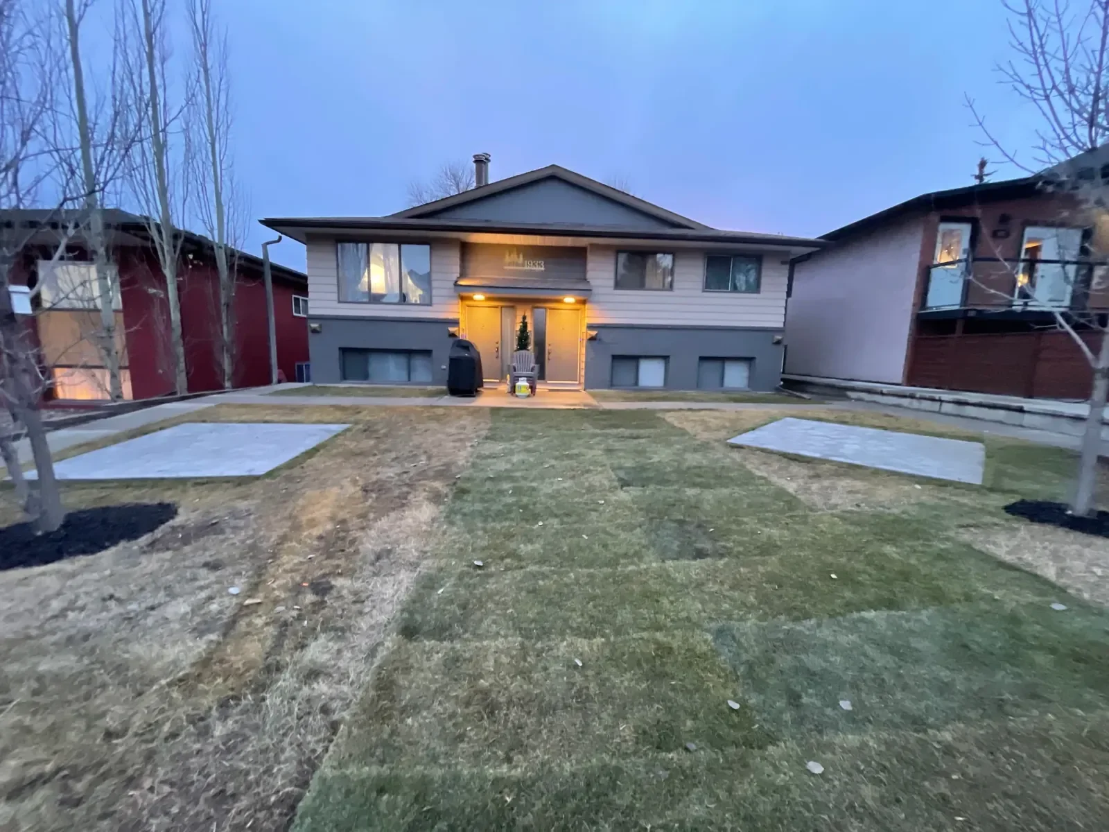 Front yard landscaping featuring fresh sod installation and concrete patio pads at a residential home in Calgary.
