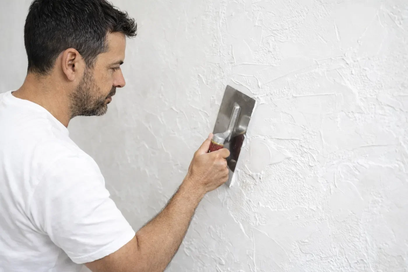 Craftsman applying Venetian plaster to a wall using traditional hand-trowel techniques in Calgary
