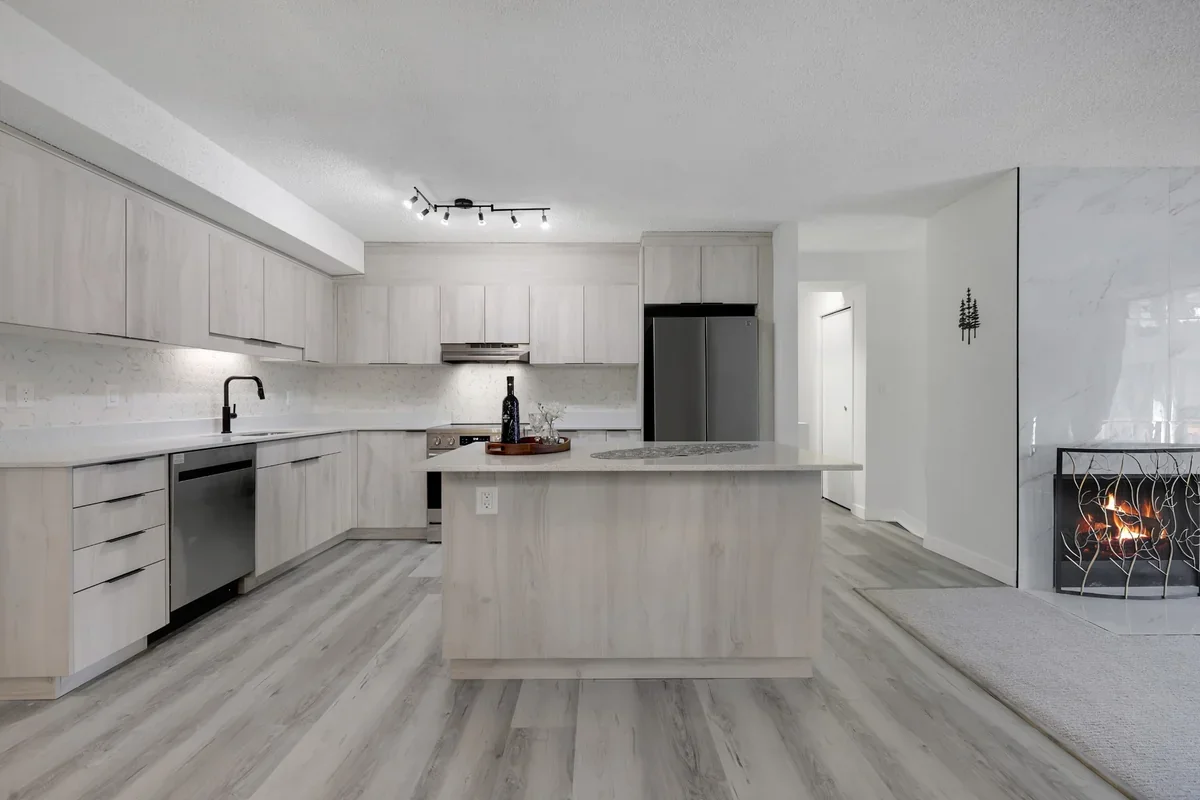 Contemporary kitchen renovation in Calgary featuring custom light wood cabinetry, quartz countertops, a spacious island, stainless steel appliances, luxury vinyl plank flooring, and premium modern finishes by Da Vinci Contracting.