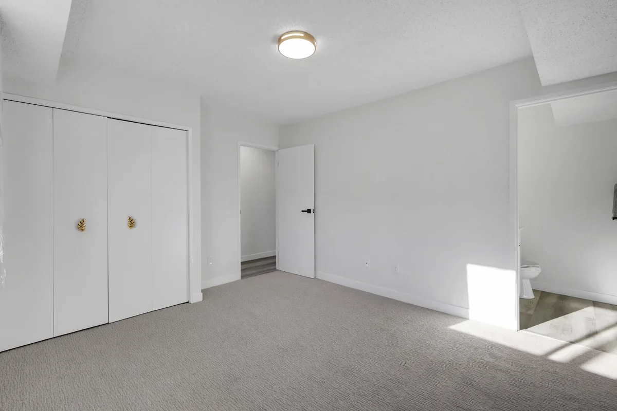 Master bedroom renovation in Calgary with fresh paint, new carpet, updated trim, spacious closet, and ensuite bathroom completed by Da Vinci Contracting.