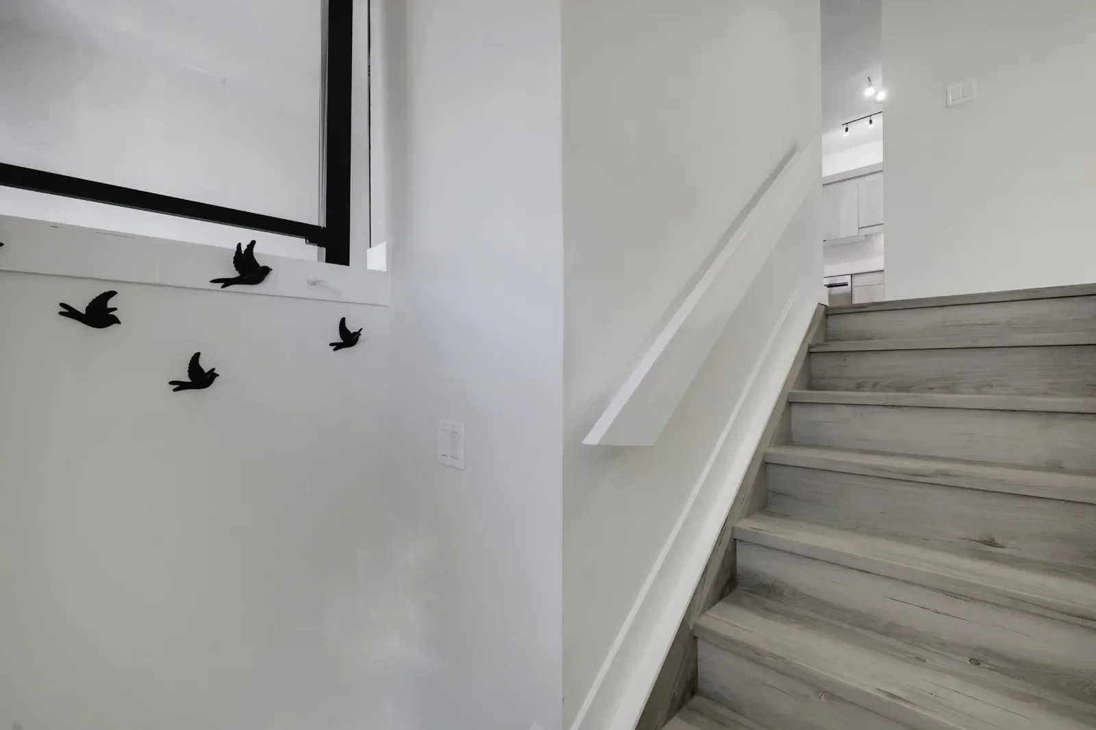 A modern interior staircase renovation featuring sleek grey wood steps, crisp white walls, and a minimalist handrail design. This clean and functional upgrade enhances both the style and flow of the home, creating a bright and contemporary transition