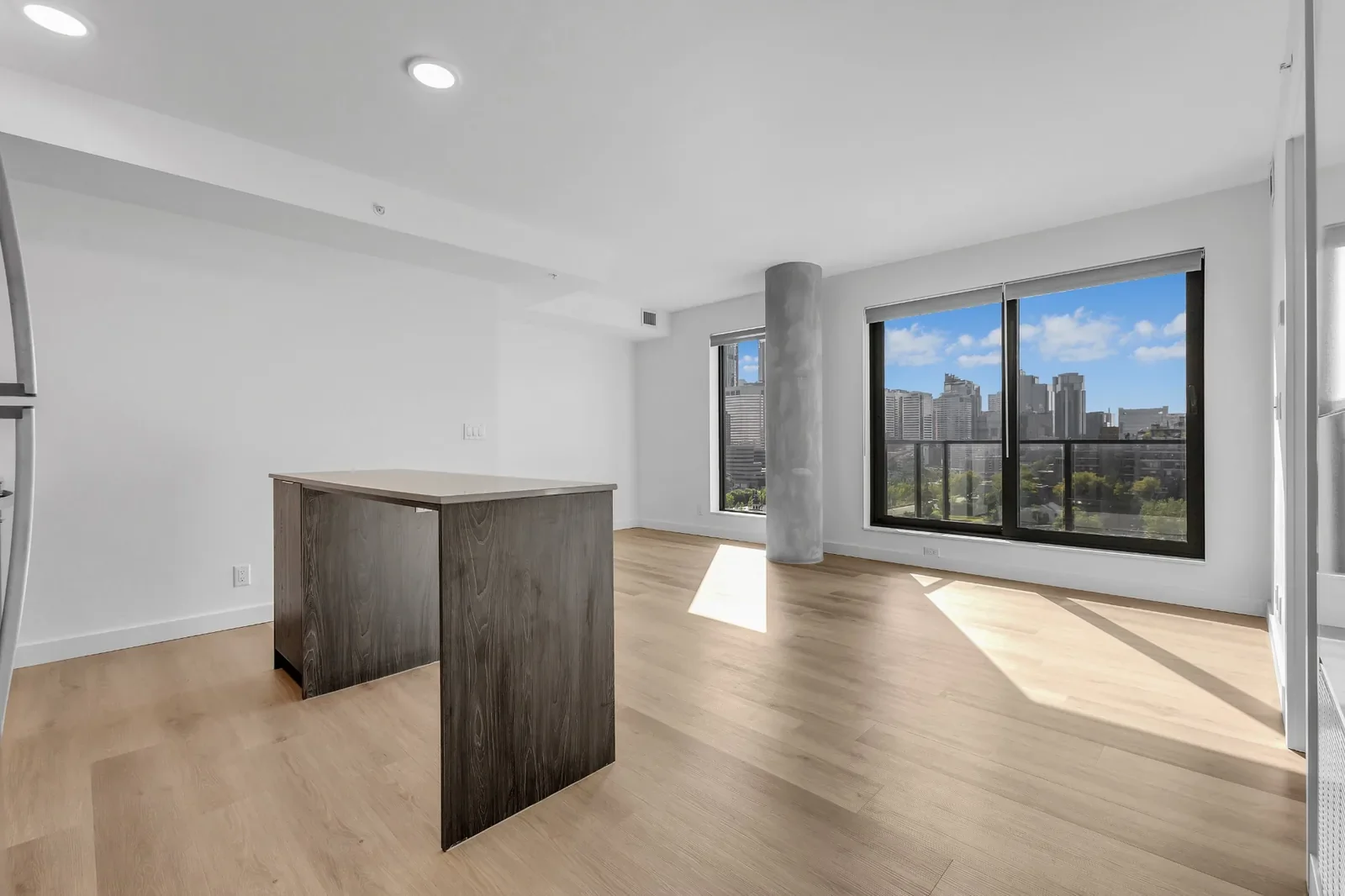 Modern flooring installation featuring light hardwood floors in a bright open-concept living space with large windows in a Calgary condo.