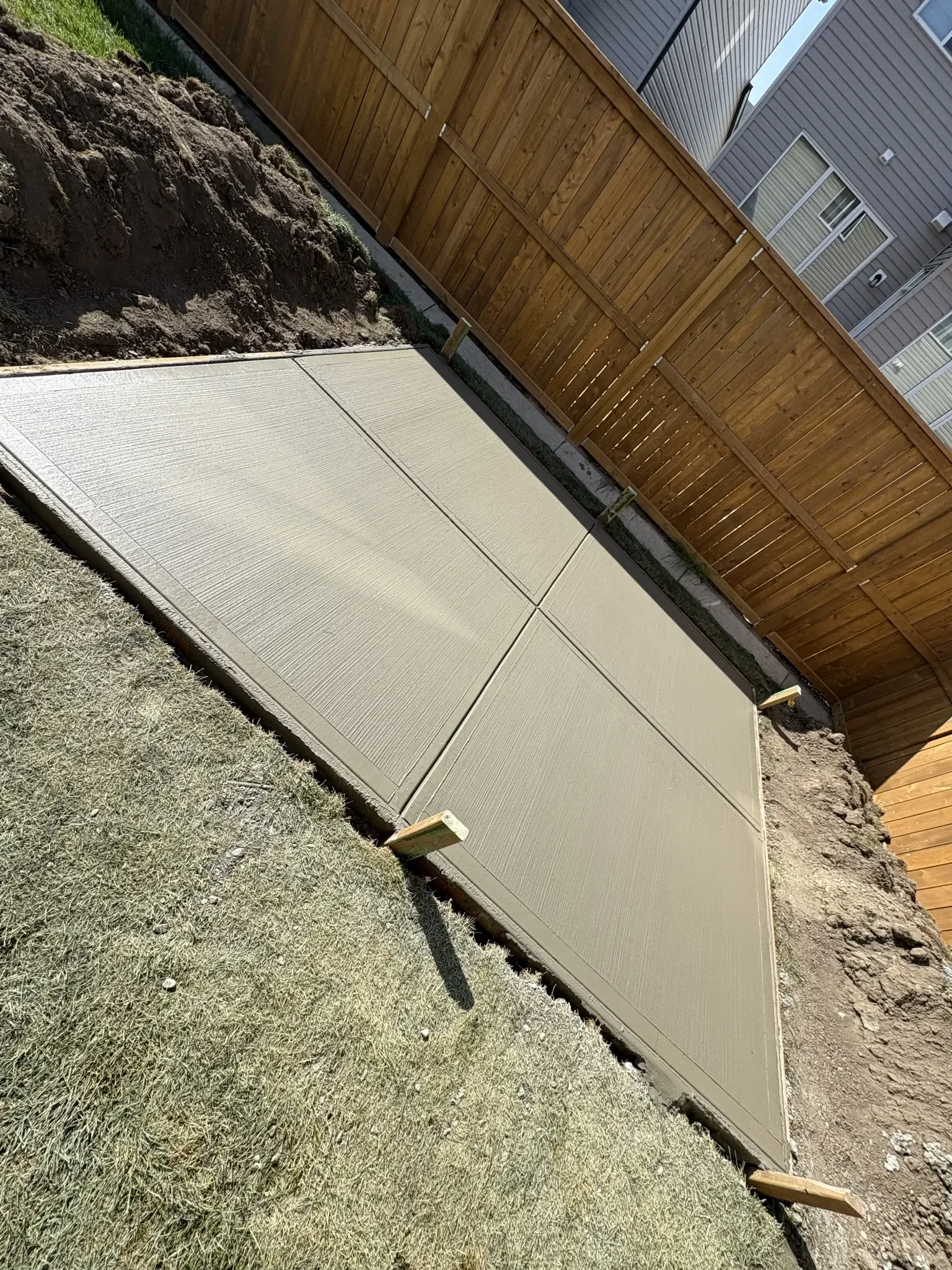 Concrete backyard slab poured and finished with a broom texture and clean control joints, providing a durable, slip-resistant surface ready for long-term outdoor use.