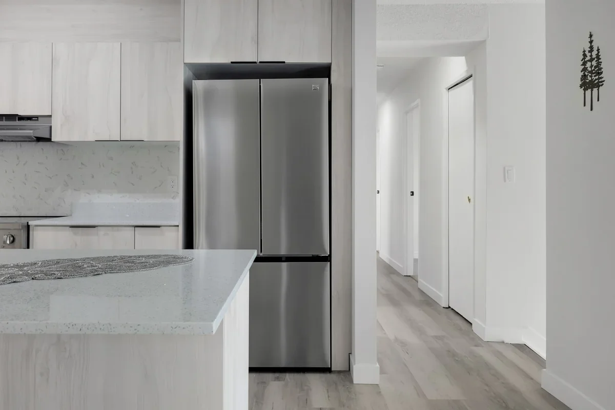 Modern kitchen renovation in Calgary showcasing quartz countertops, custom cabinetry, stainless steel appliances, luxury vinyl plank flooring, and contemporary finishes completed by Da Vinci Contracting.