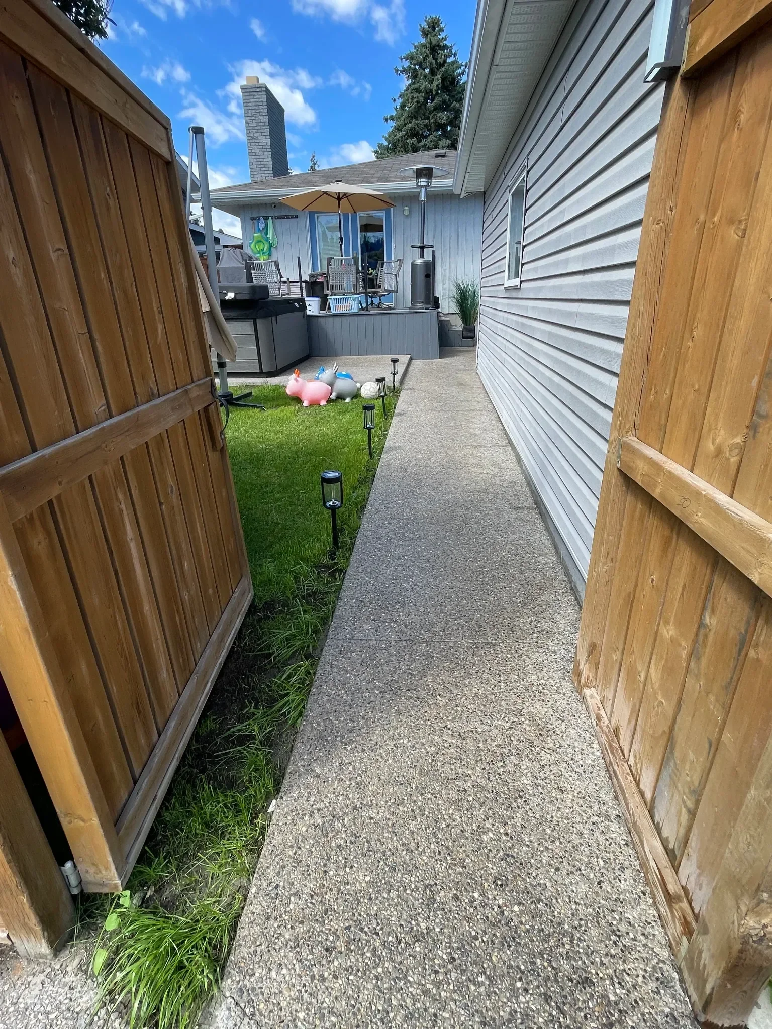 Exposed aggregate concrete walkway providing a durable, slip-resistant path along the side of the home. This clean, modern finish offers long-lasting performance and improved drainage, making it ideal for Calgary residential walkways and access paths