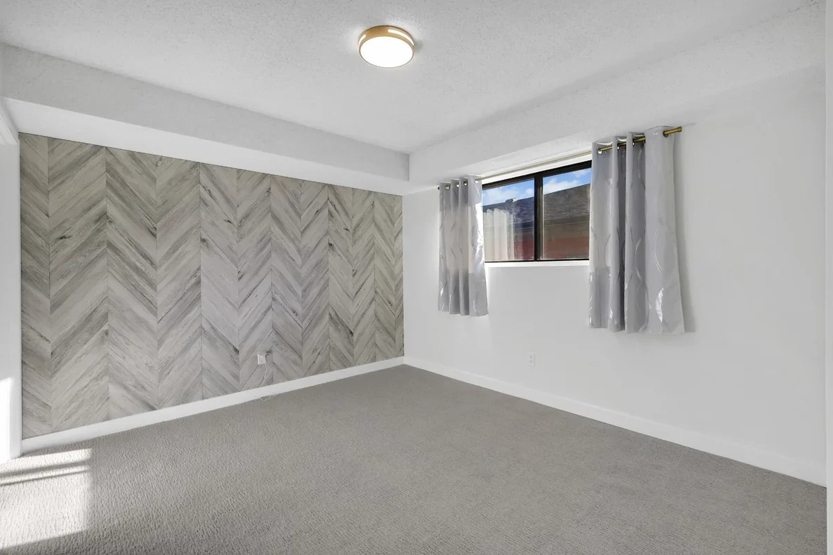 Master bedroom renovation in Calgary showcasing a custom herringbone feature wall, fresh paint, new carpet, updated trim, and bright contemporary finishes completed by Da Vinci Contracting.