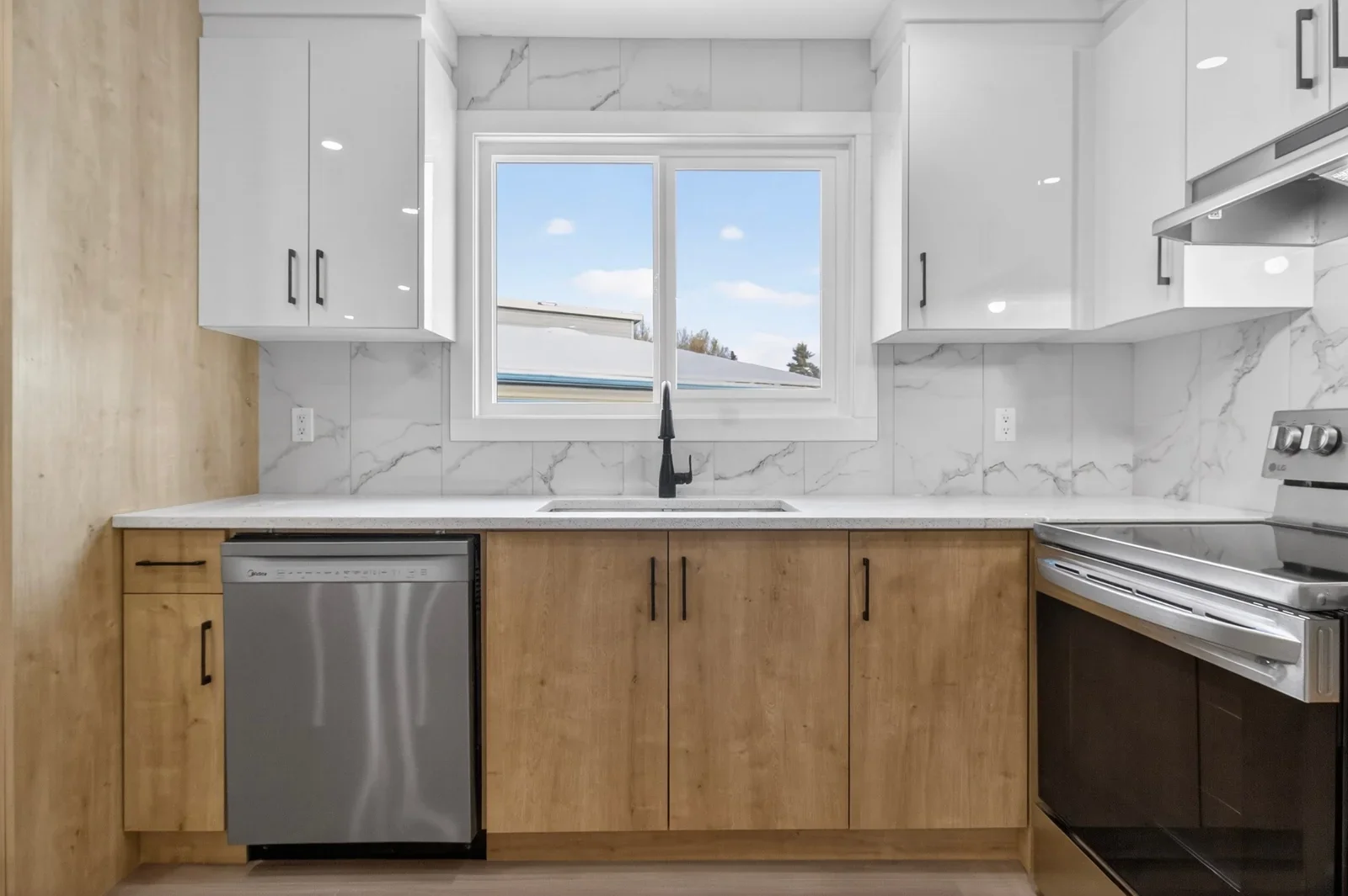 Modern kitchen renovation in Calgary featuring white upper cabinets, wood lower cabinetry, quartz countertops, and marble-style backsplash