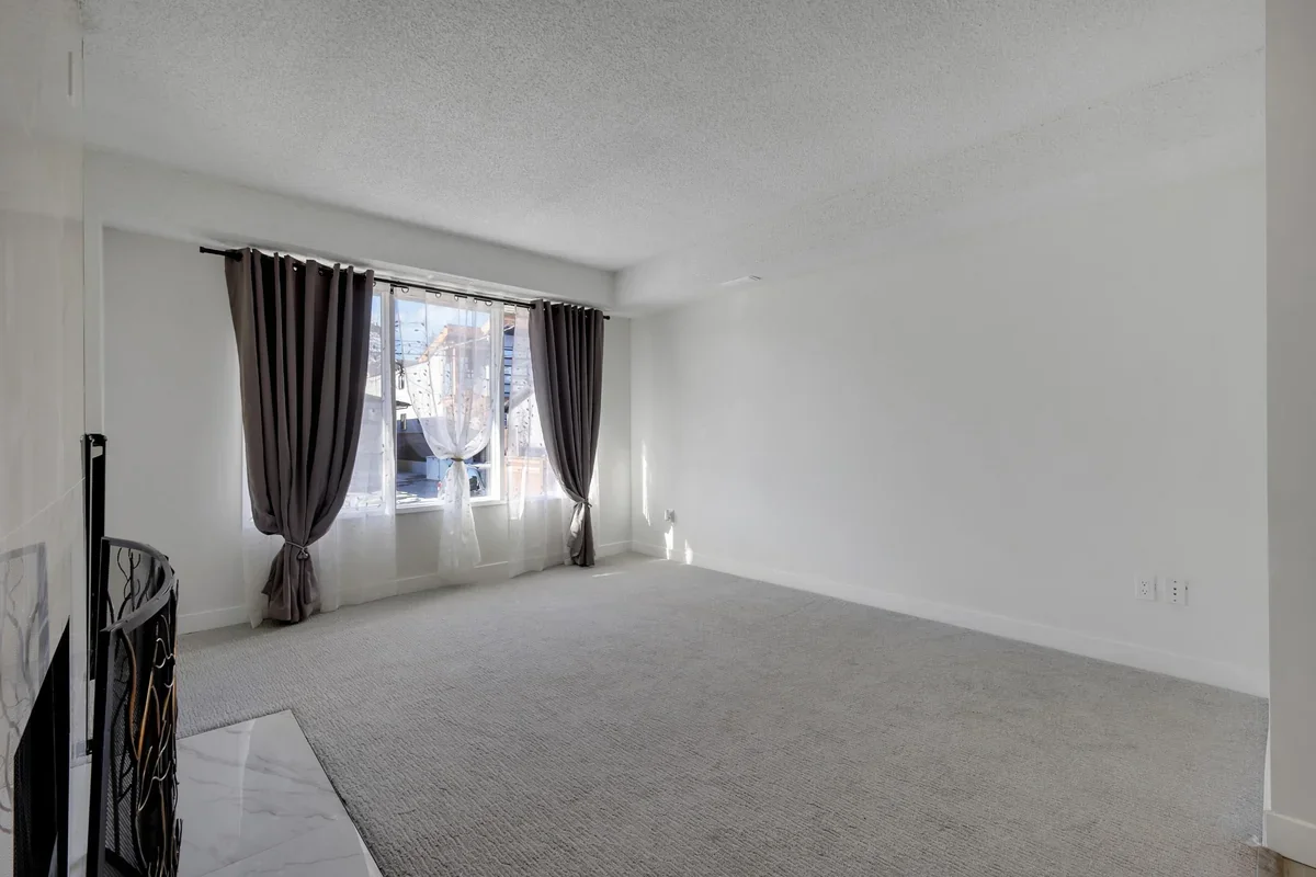 Modern living room renovation in Calgary with new carpet, fresh paint, large windows, updated trim, and clean contemporary finishes completed by Da Vinci Contracting.