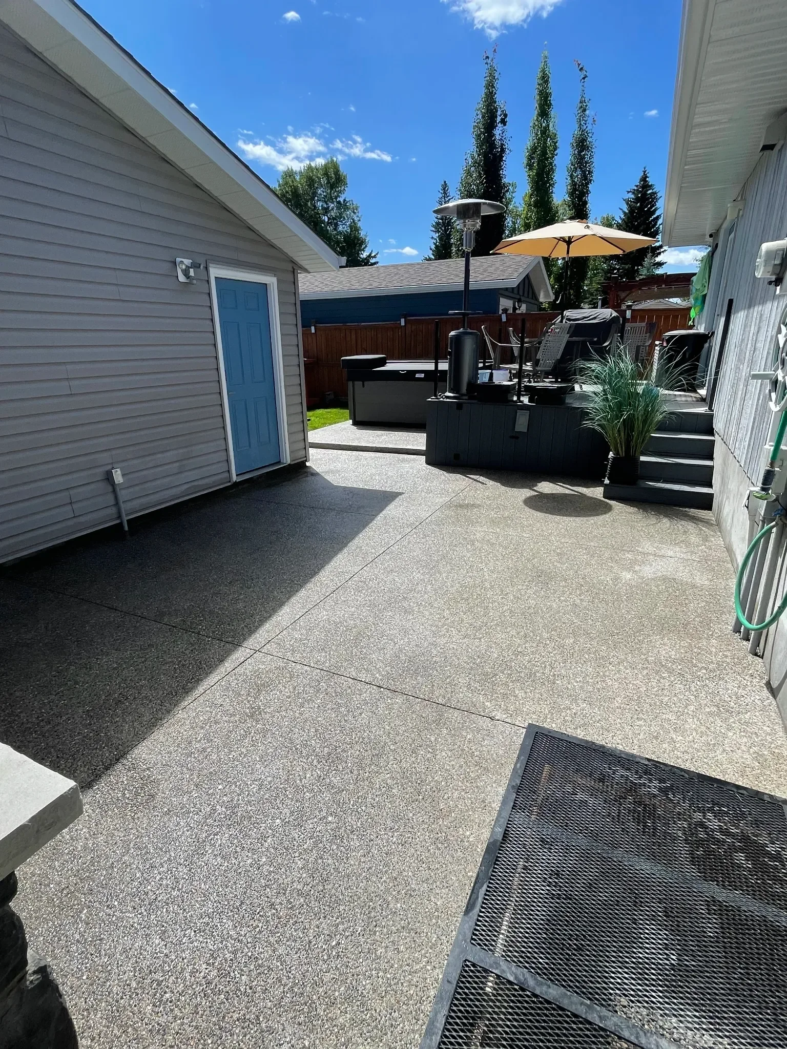 Large exposed aggregate concrete backyard patio designed for outdoor living, featuring clean control joints and a durable, slip-resistant finish ideal for entertaining and relaxation.
