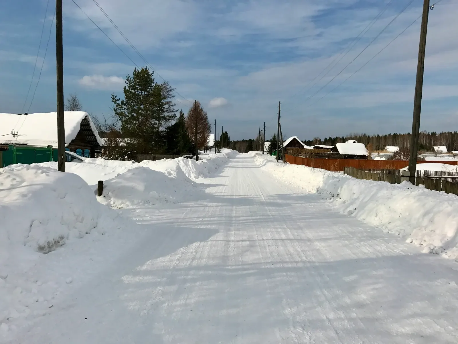 Snow removal after photo showing a cleared residential road with snowbanks on both sides.