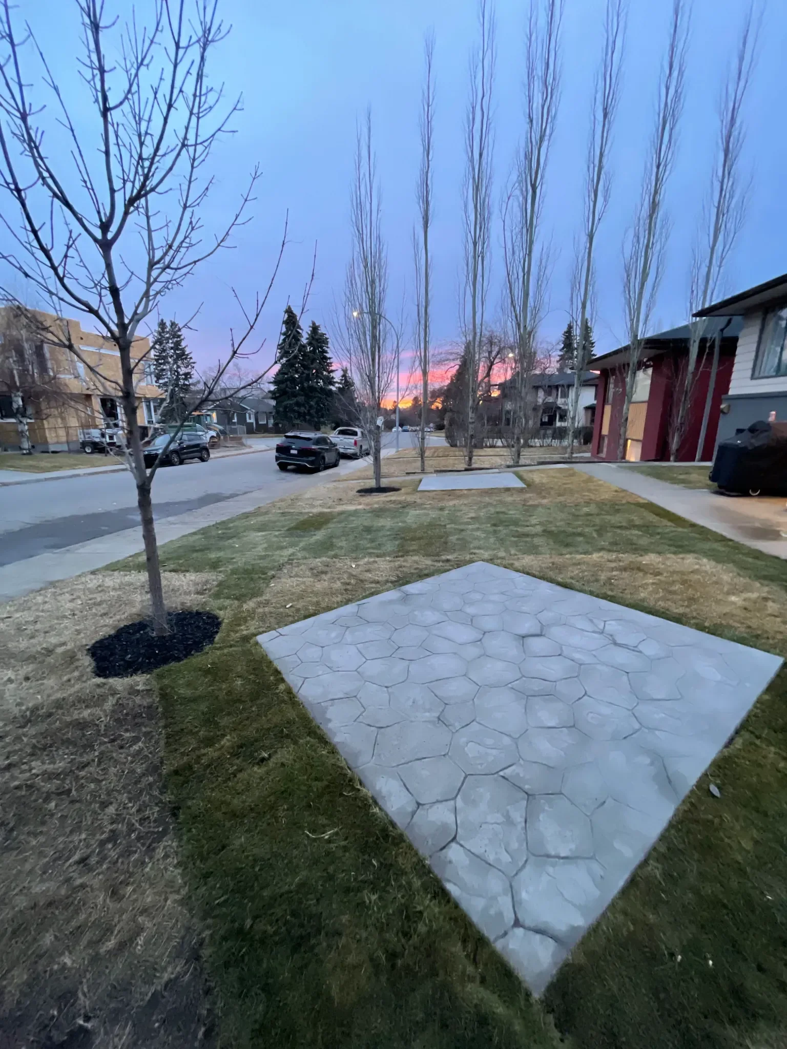 Front yard landscaping featuring concrete patio pads, clean walkways, and fresh sod at a residential home in Calgary.