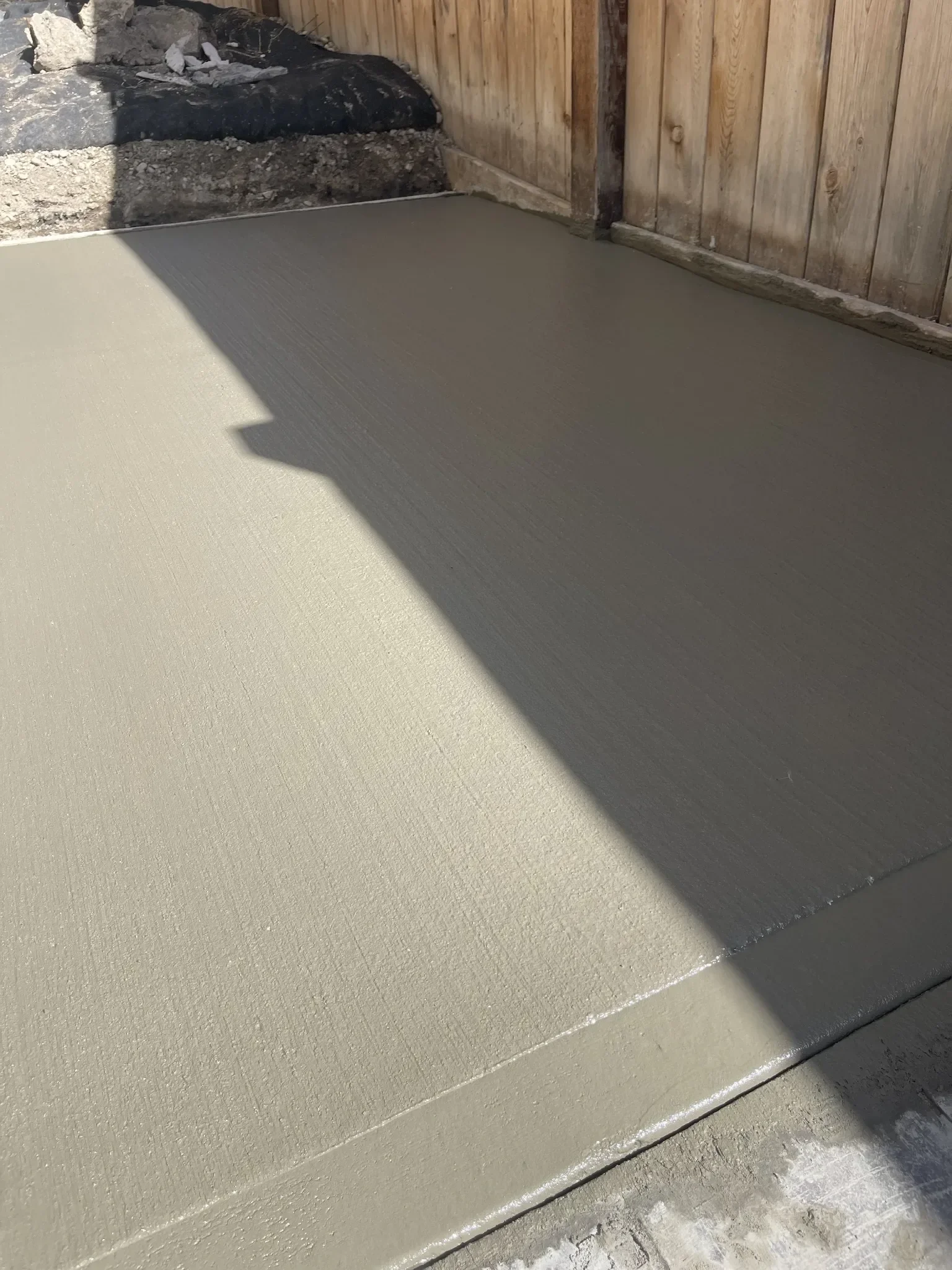 Smooth-finished concrete slab poured in a side yard to create a clean, durable walking surface with proper grading for drainage.
