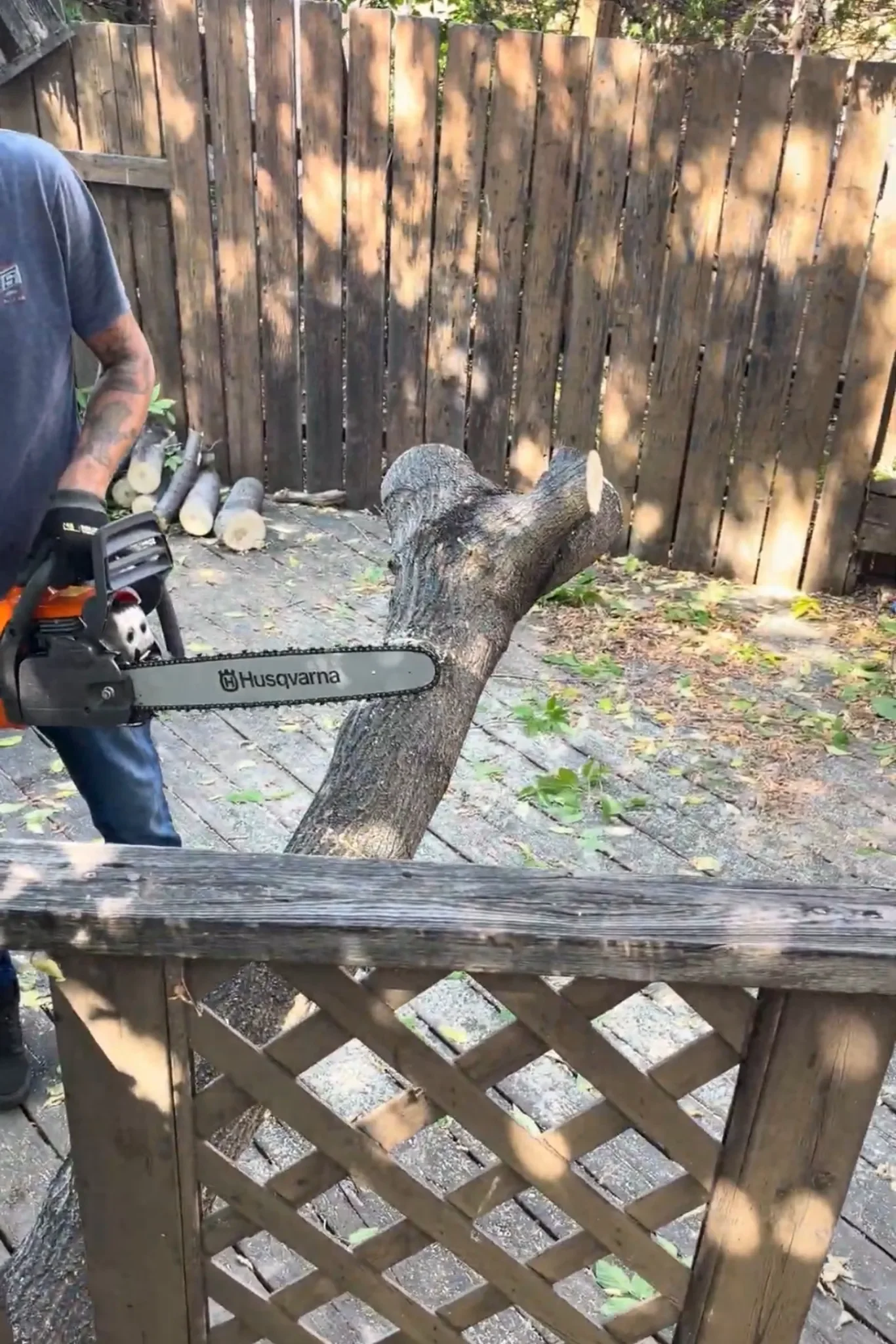 Backyard tree removal showing a professional cutting a large tree trunk with a chainsaw during residential tree removal in Calgary.