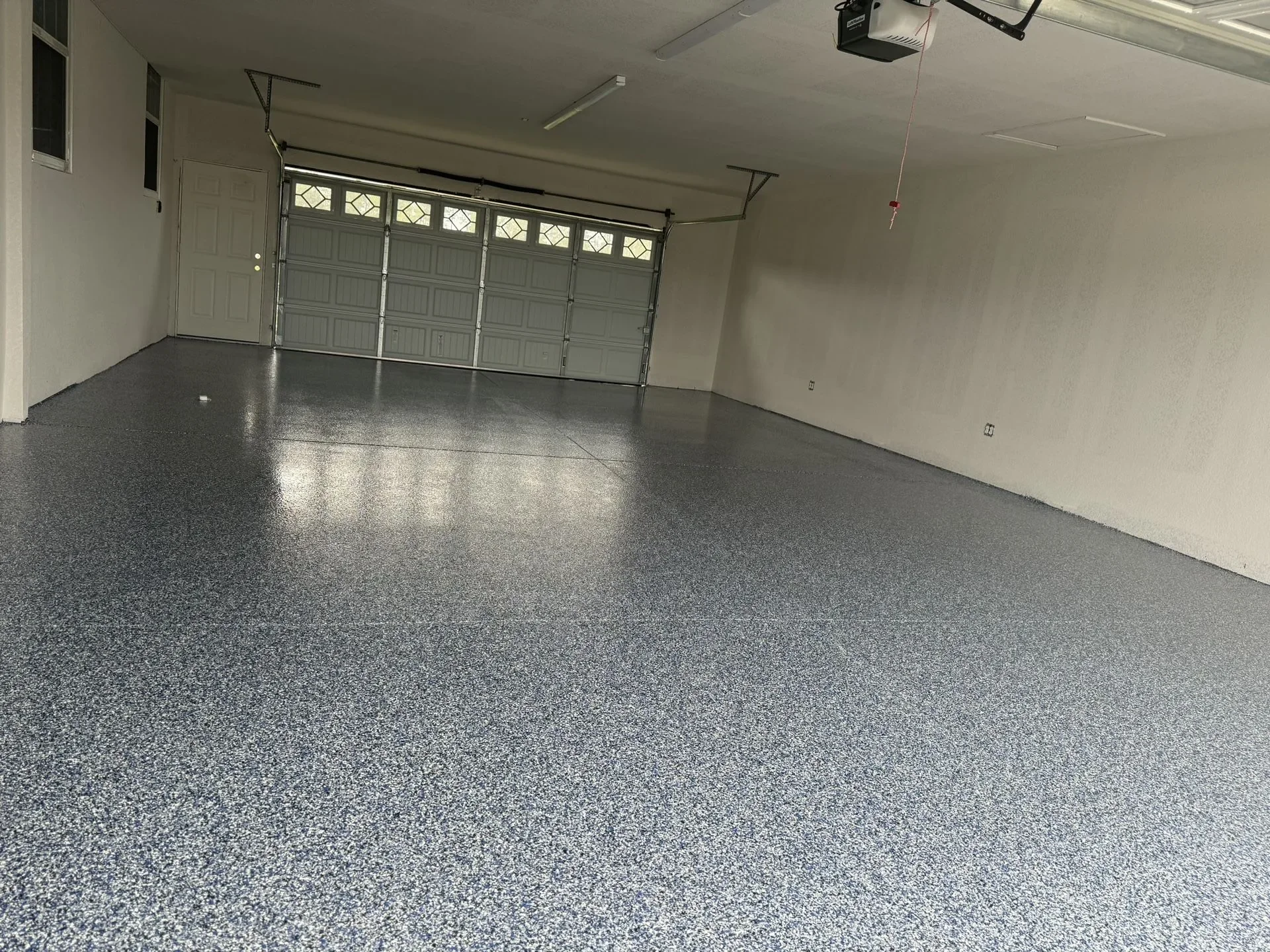 Spacious garage with a professionally installed epoxy floor featuring a durable grey flake finish for a clean, modern look.