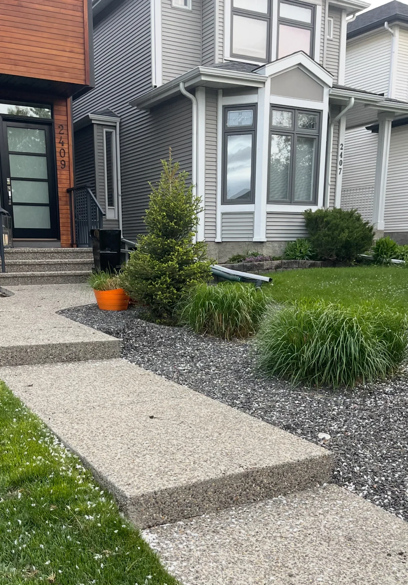 Exposed aggregate concrete walkway and front steps in Calgary with clean edges, modern landscaping, and finished residential exterior