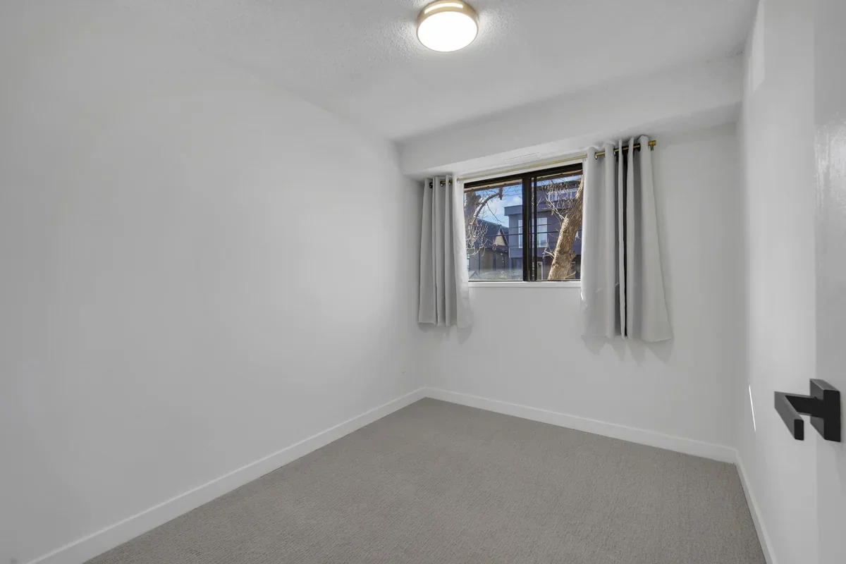 Modern bedroom renovation in Calgary with fresh paint, new carpet, updated trim, large windows, and clean contemporary finishes completed by Da Vinci Contracting.