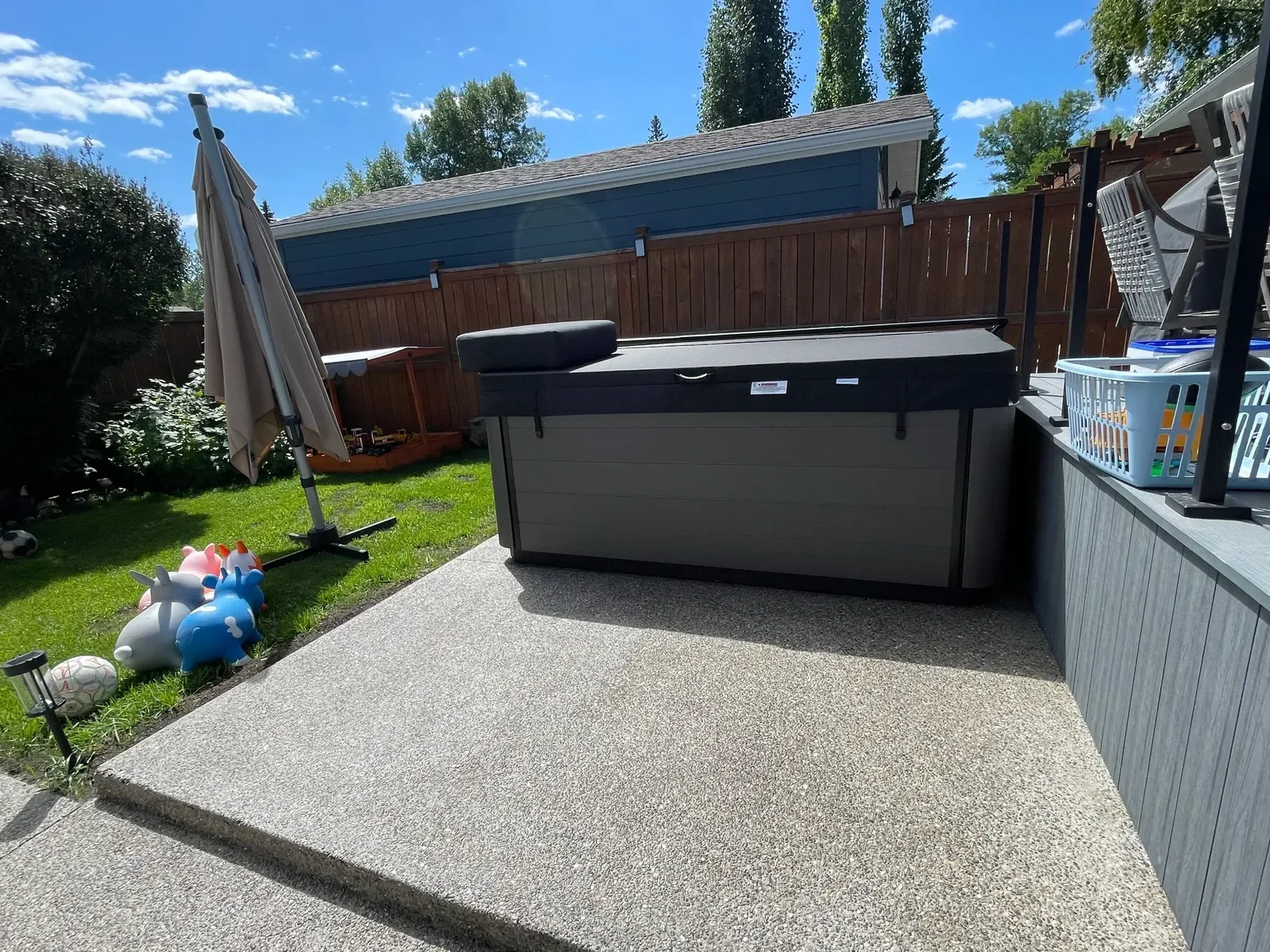 Exposed aggregate concrete patio featuring a smooth, durable finish with clean edges, designed to support a hot tub and outdoor living space. This backyard concrete project offers excellent drainage, slip resistance, and a modern aesthetic perfect fo