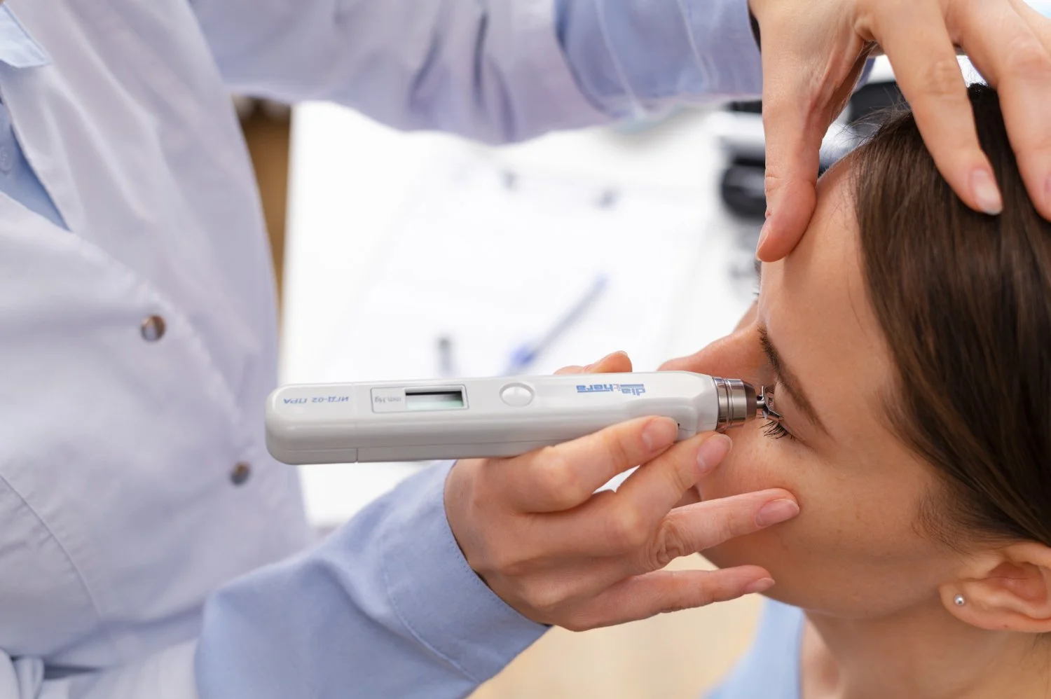 A healthcare professional using an otoscope to examine a woman's eyes.