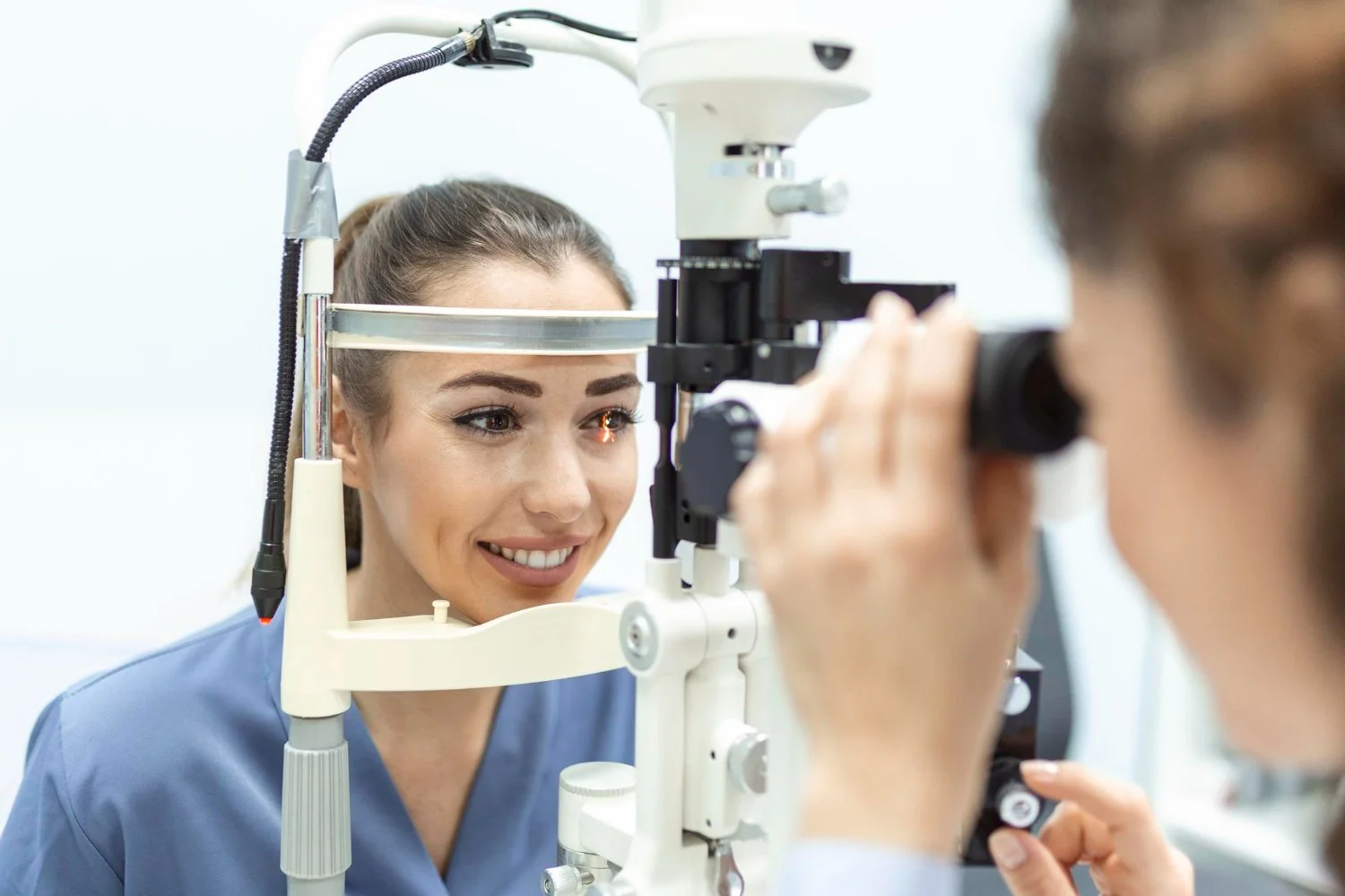 Optometrist examining patient's eyes using a slit lamp at an eye clinic.