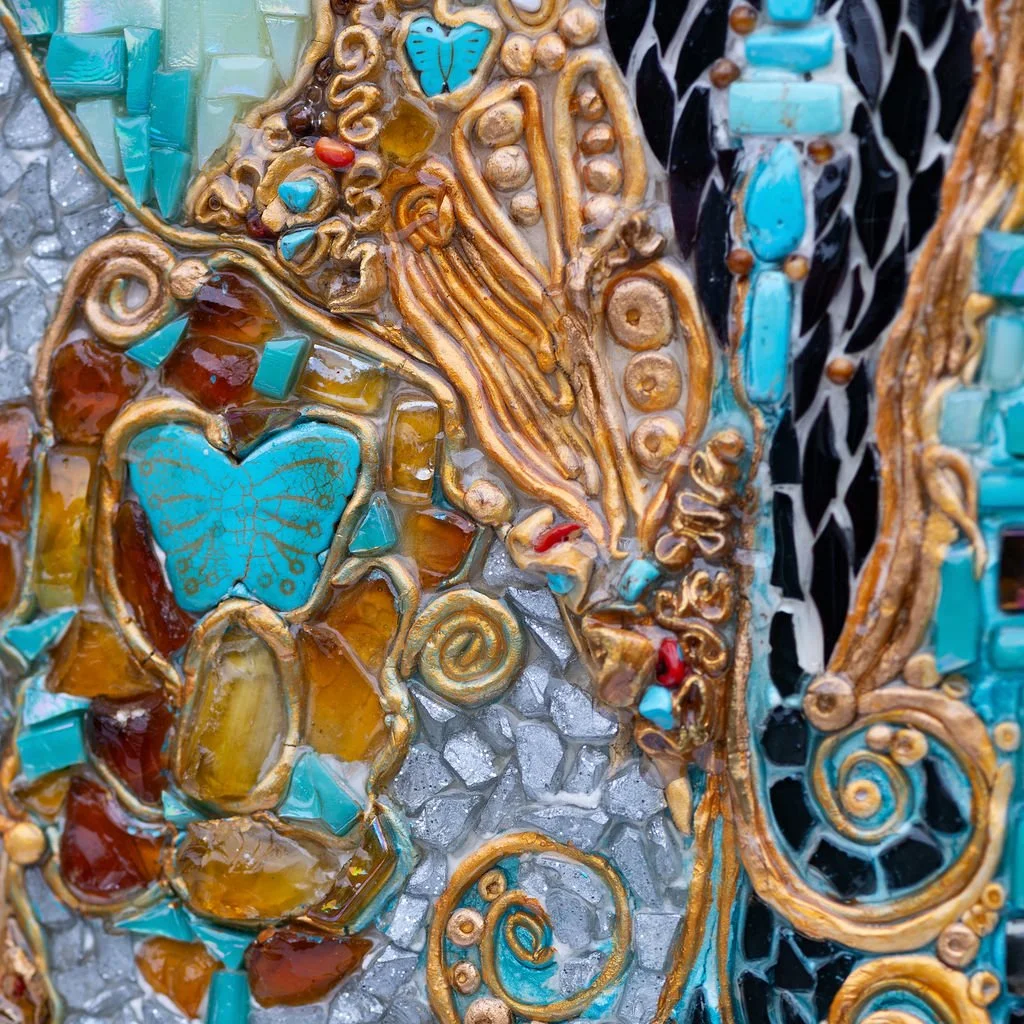 Detail of a colorful mosaic featuring turquoise butterflies, amber stones, and swirling gold accents on a textured background.
