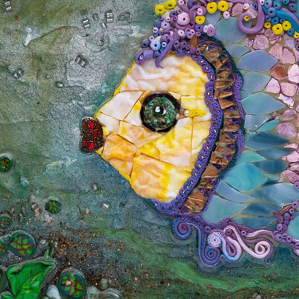 Close-up of a colorful mosaic art piece depicting a butterfly's head with detailed eyes, antennae, and wings made of various glass and tile pieces.