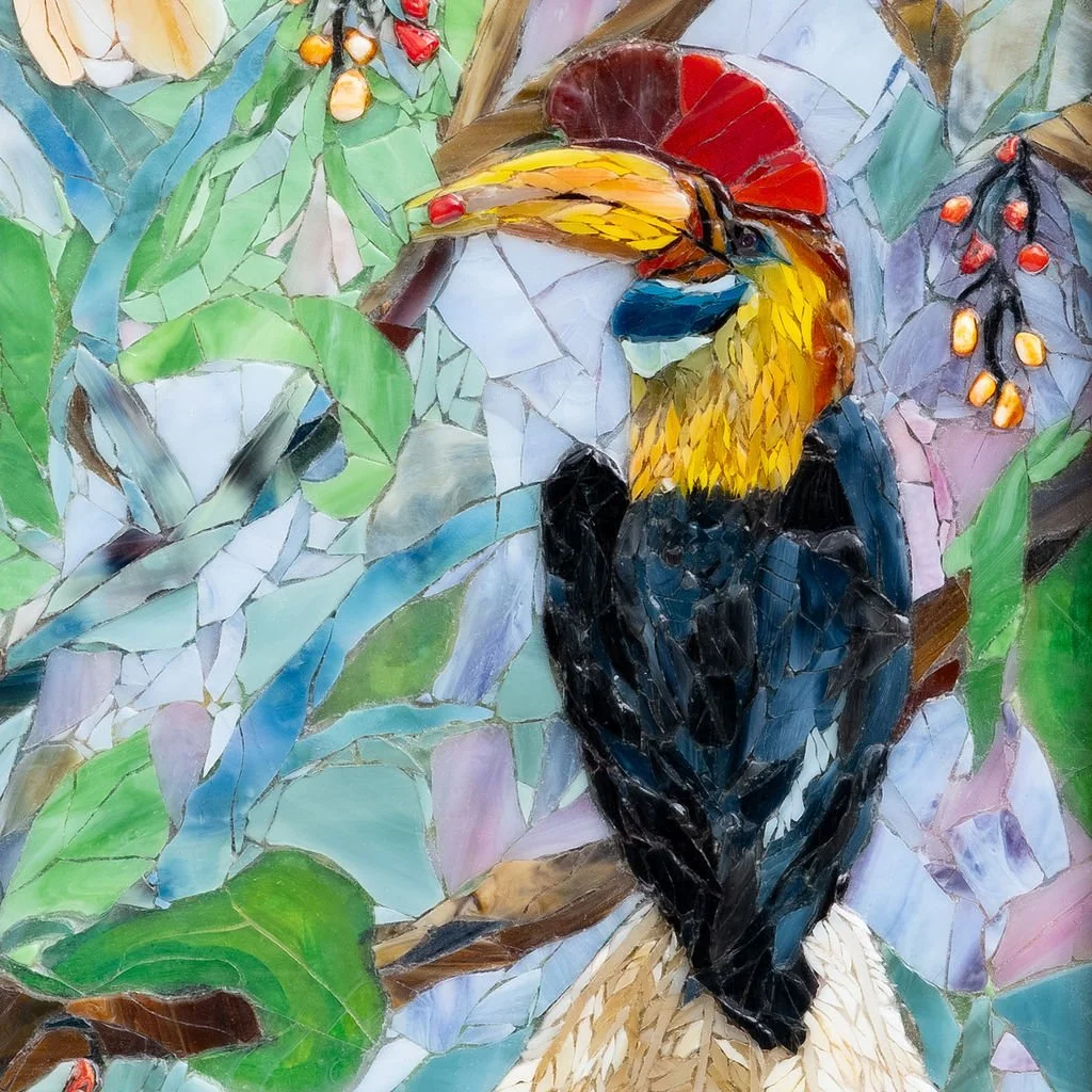 Mosaic artwork of a toucan with a bright yellow beak, surrounded by green leaves and colorful berries.