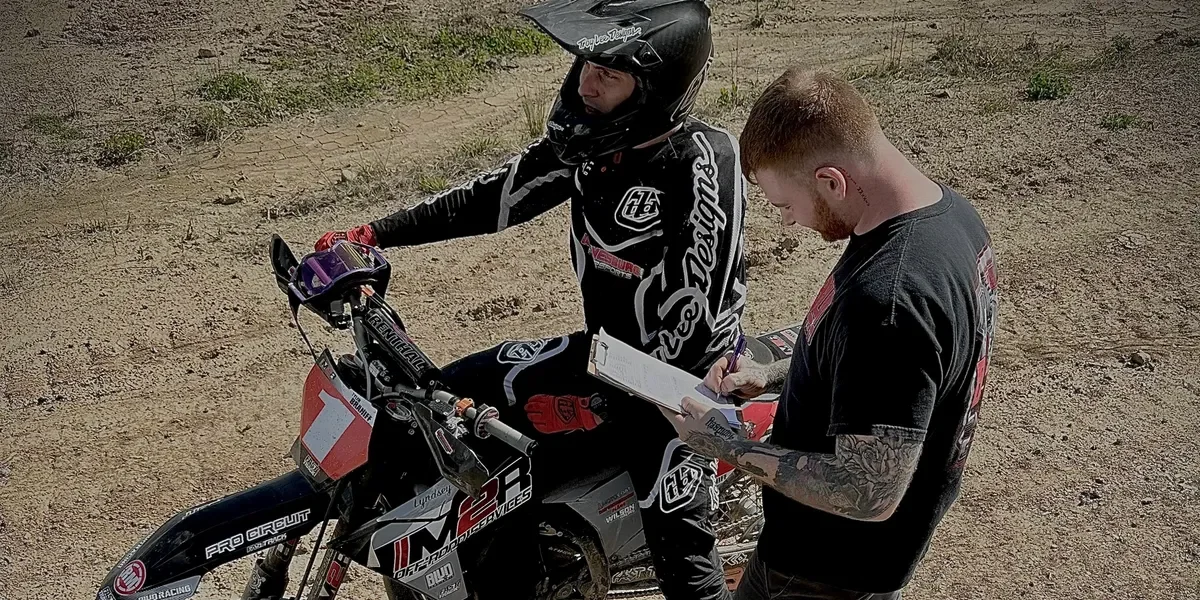A tech from M2R Offroad works with a rider at the track.